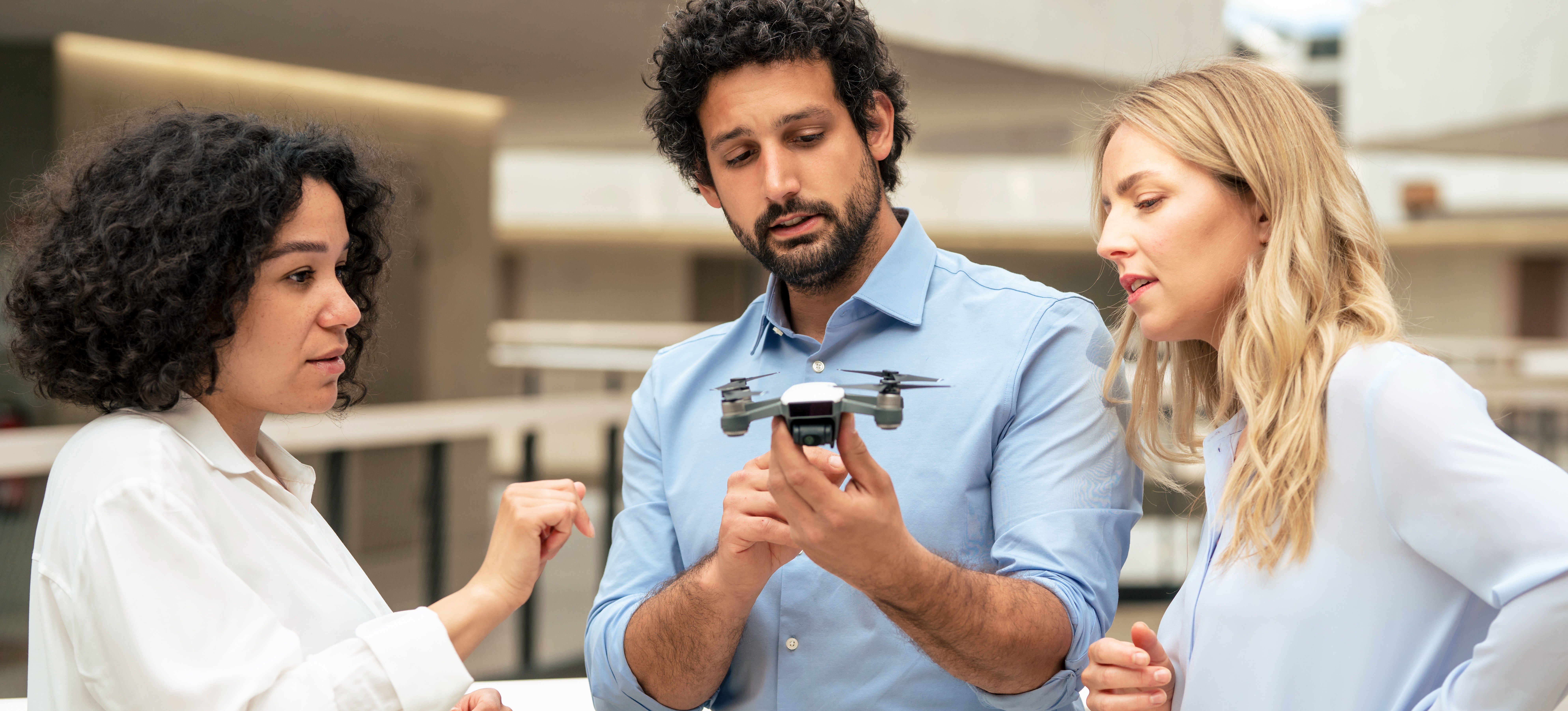 [Featured Image] Three engineers discuss simultaneous localization and mapping while looking at a drone.  