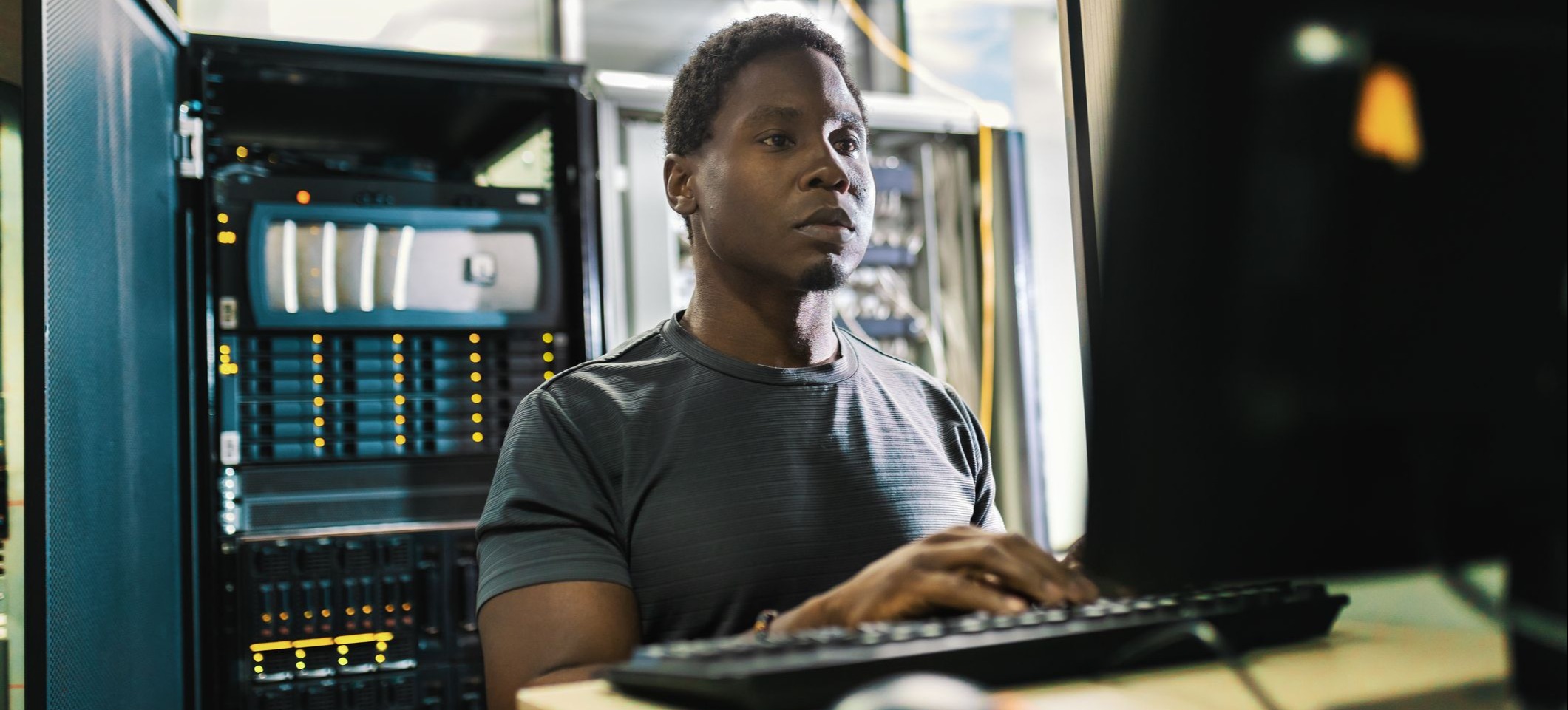 [Featured image] A computer forensics employee stands at a workstation with a server unit behind them.