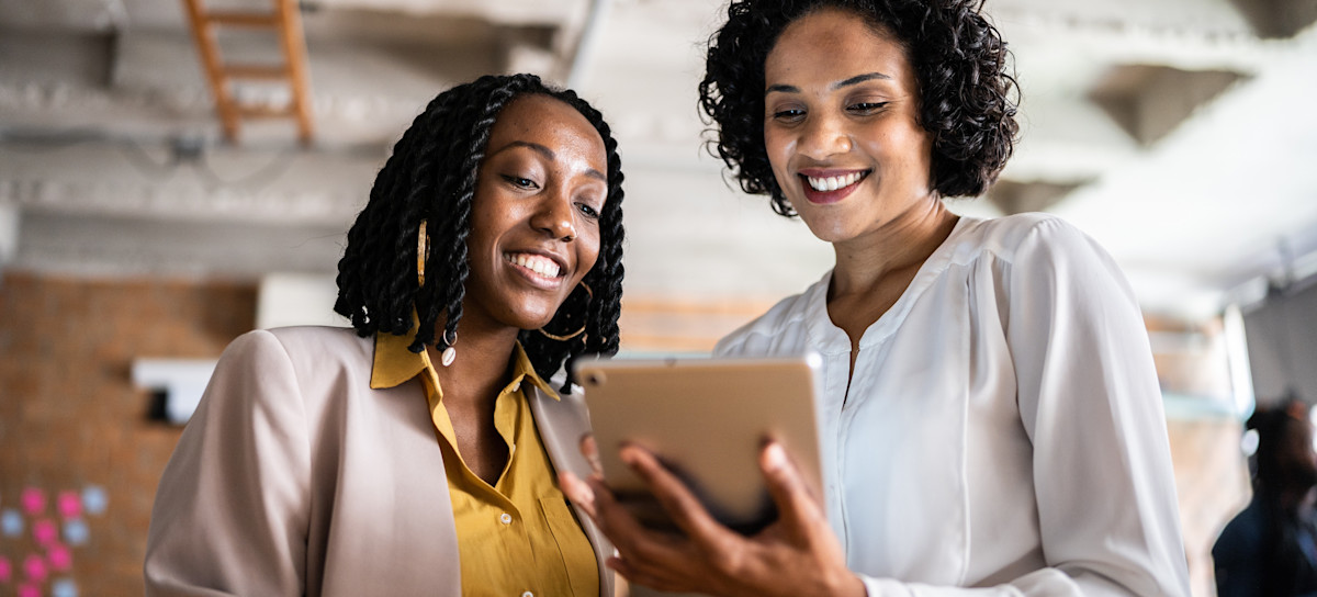 [Featured Image] Two marketers stand in their office and look at a tablet screen as they add Google Analytics to WordPress.
