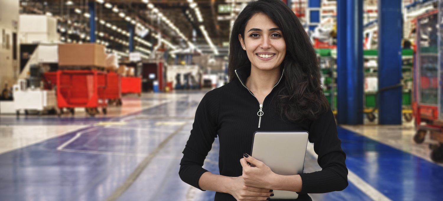 [Hauptbild] Eine Frau steht mit einem Tablet in einer großen Lagerhalle und übt eine der erlernten Fähigkeiten, mit denen sie viel Geld verdienen kann.