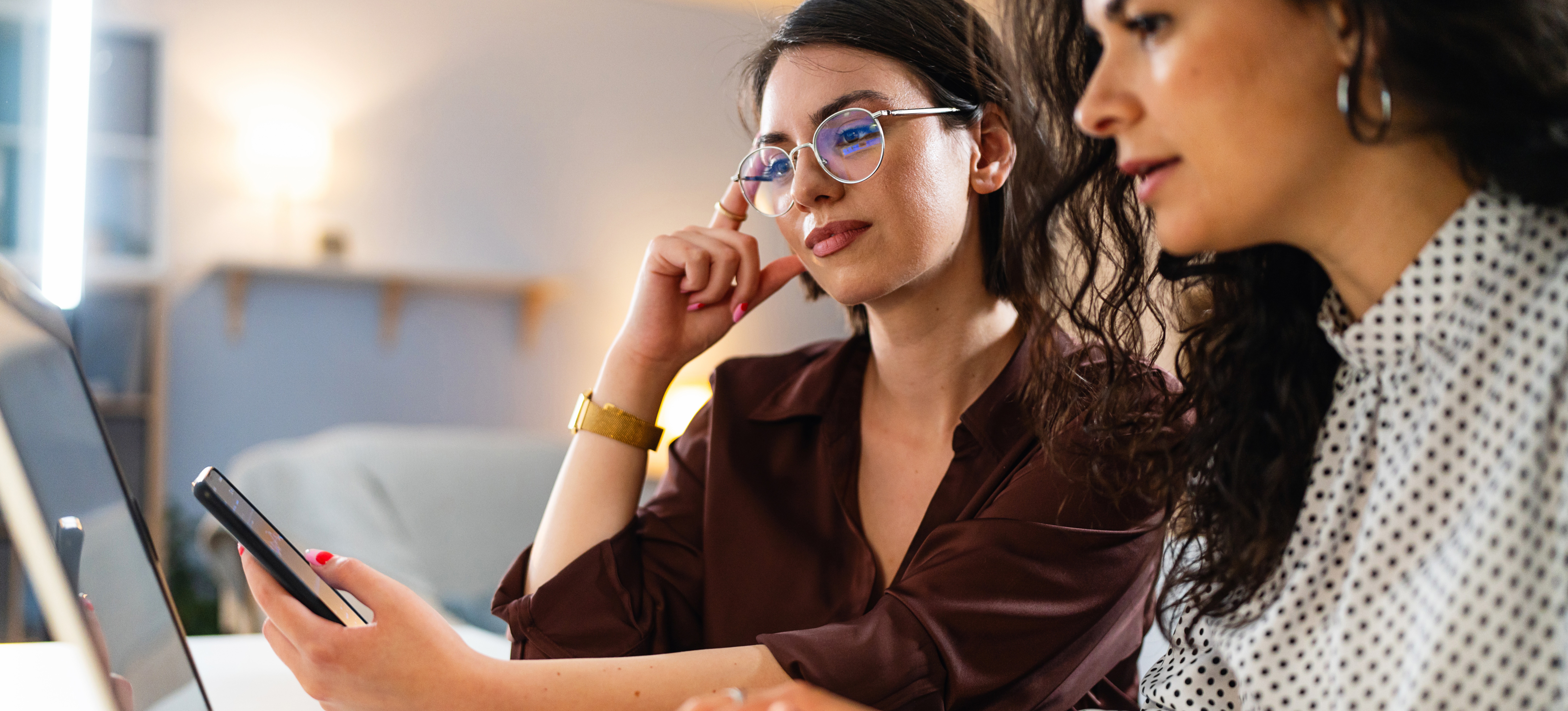 [Featured Image] Two data scientists look at a laptop and smartphone and discuss the importance of data protection and data security.
