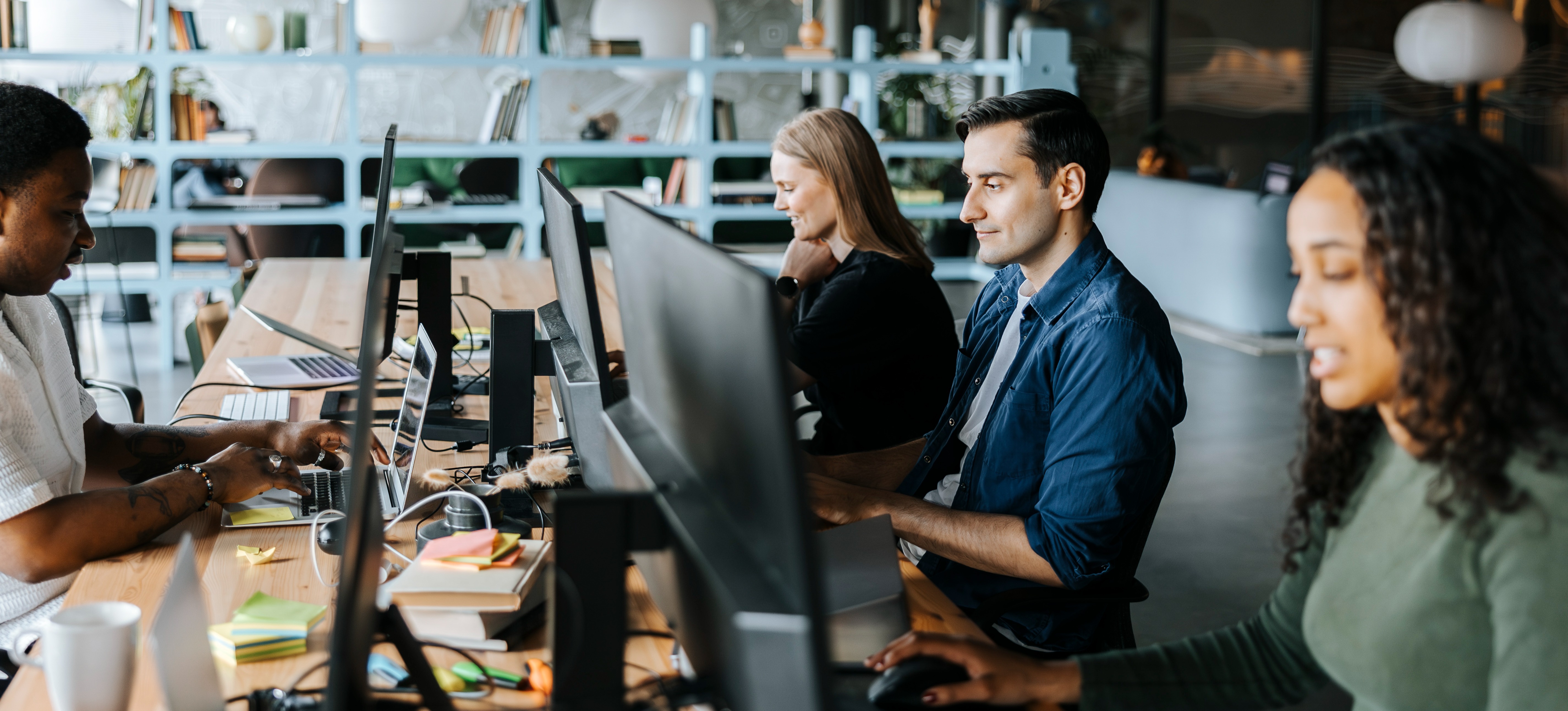[Featured Image] A group of computer programmers on separate computers, are working on the same document while using version control to revert back to the original file.