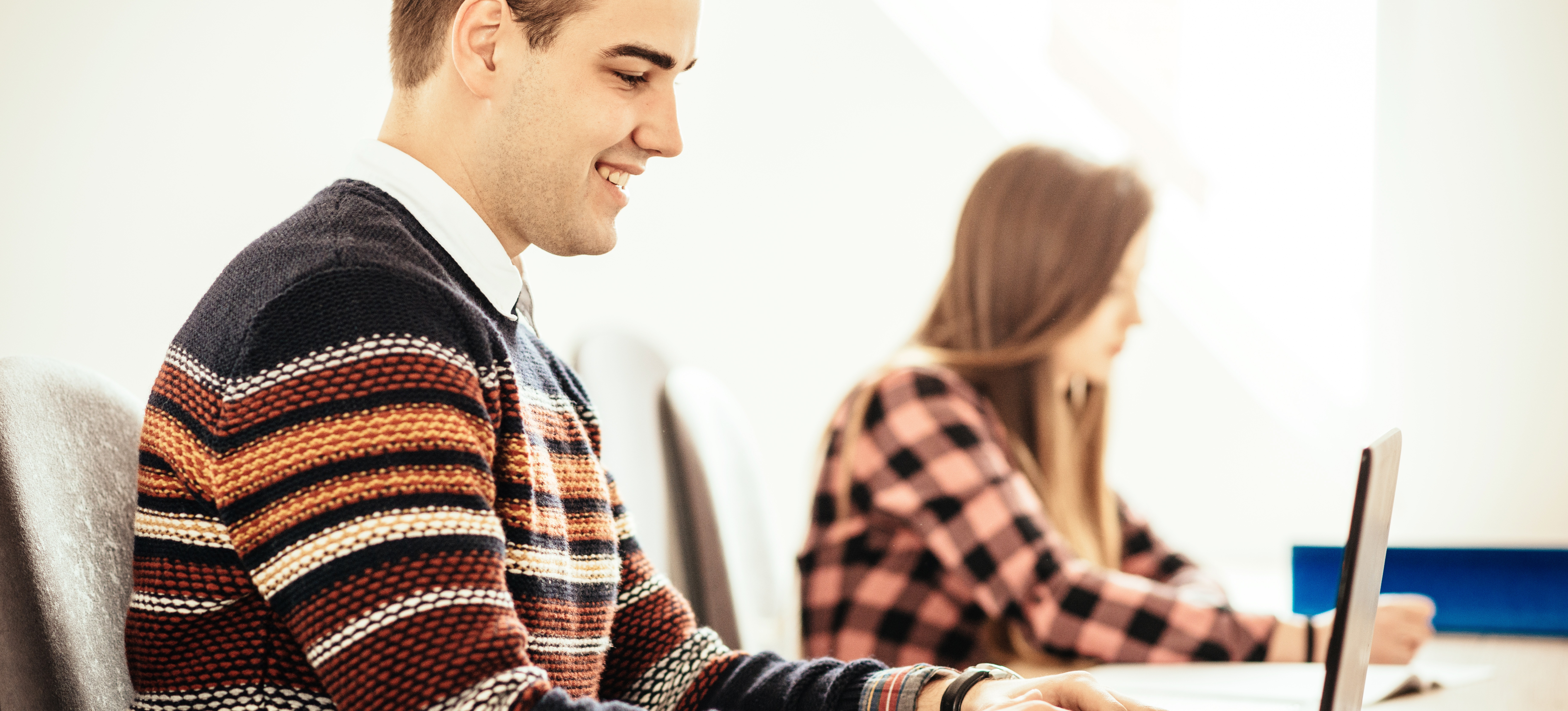 [Featured Image] A young man sits at a laptop in a required class for his computer science degree.
