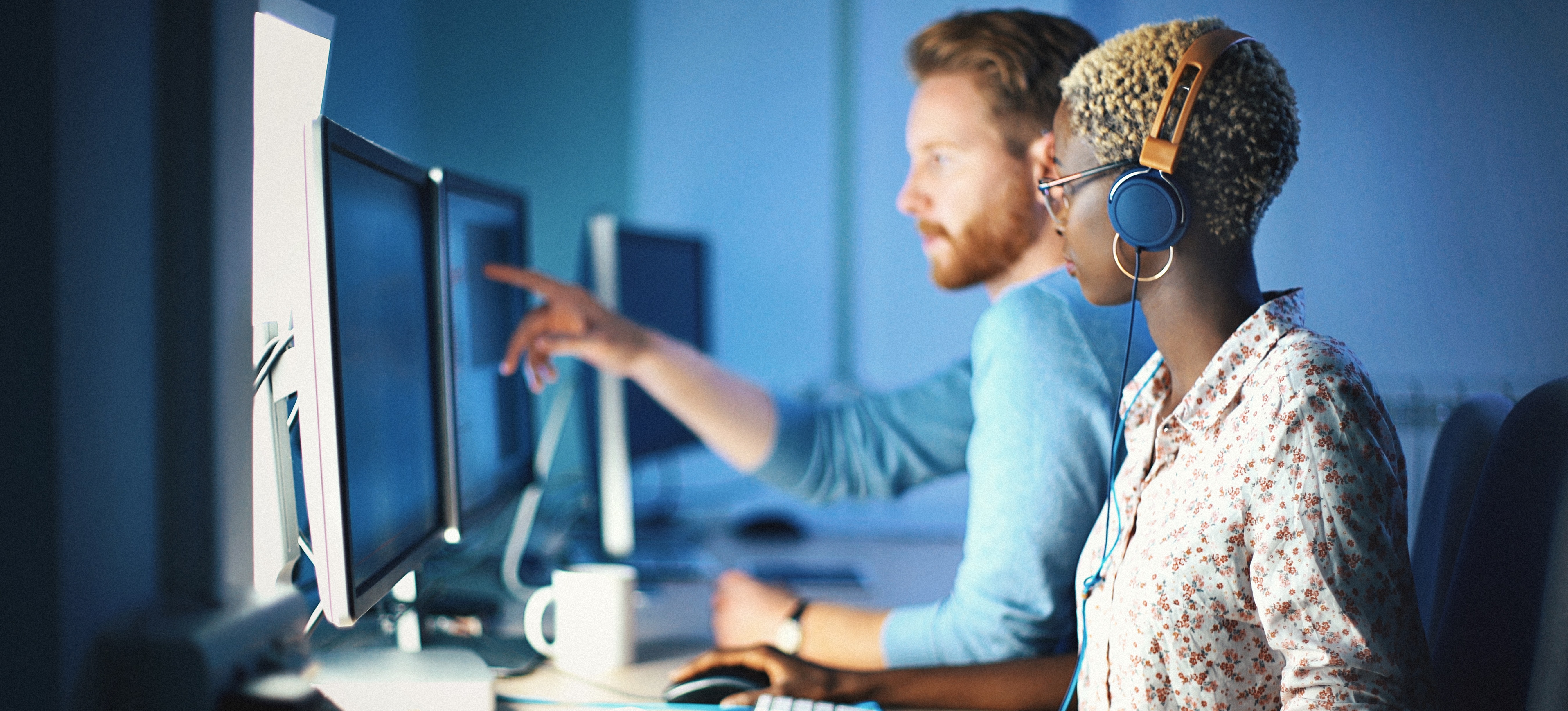 [Featured image: Two developers sitting in front of computers, using a JavaScript framework to improve productivity and collaboration.]
