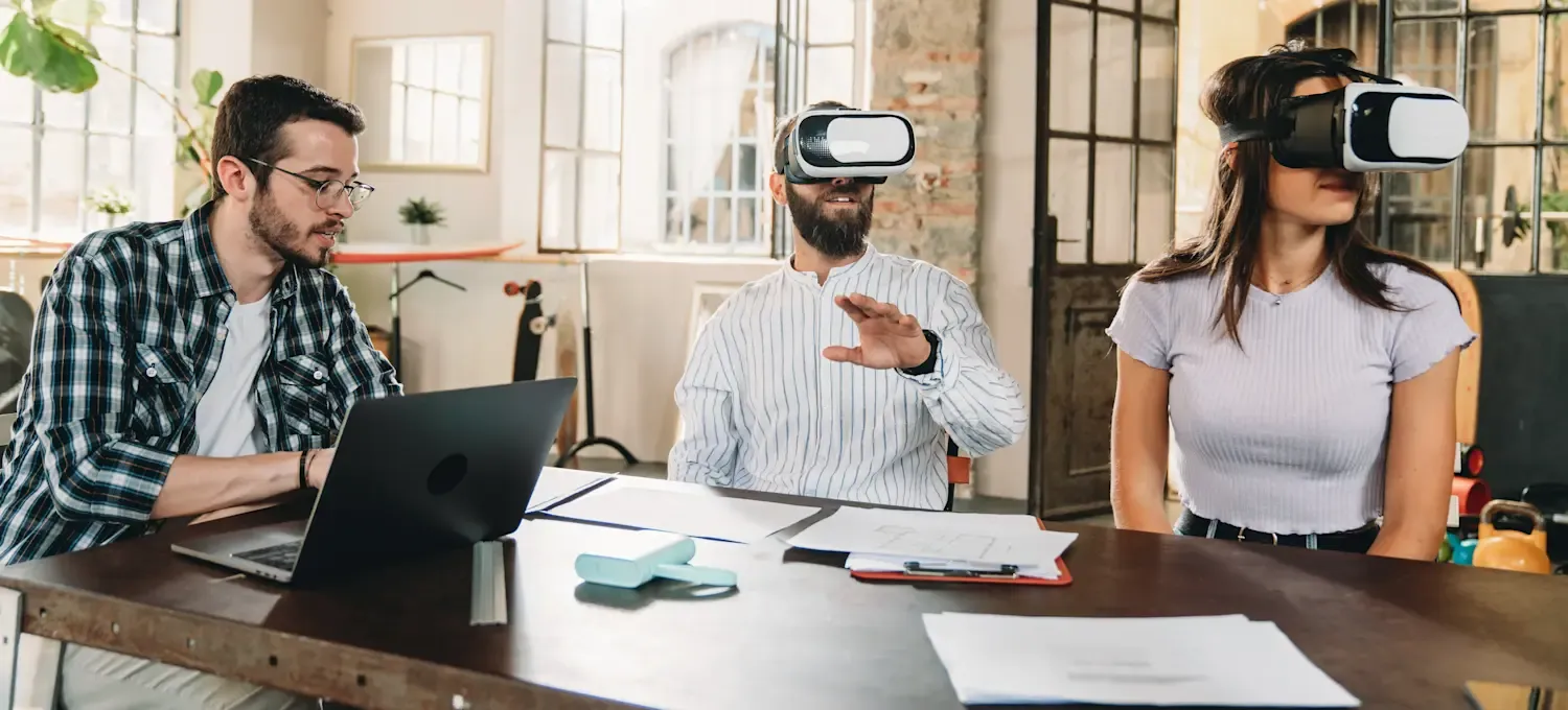 [Featured Image] Product testers sit at a conference table wearing virtual reality headsets.