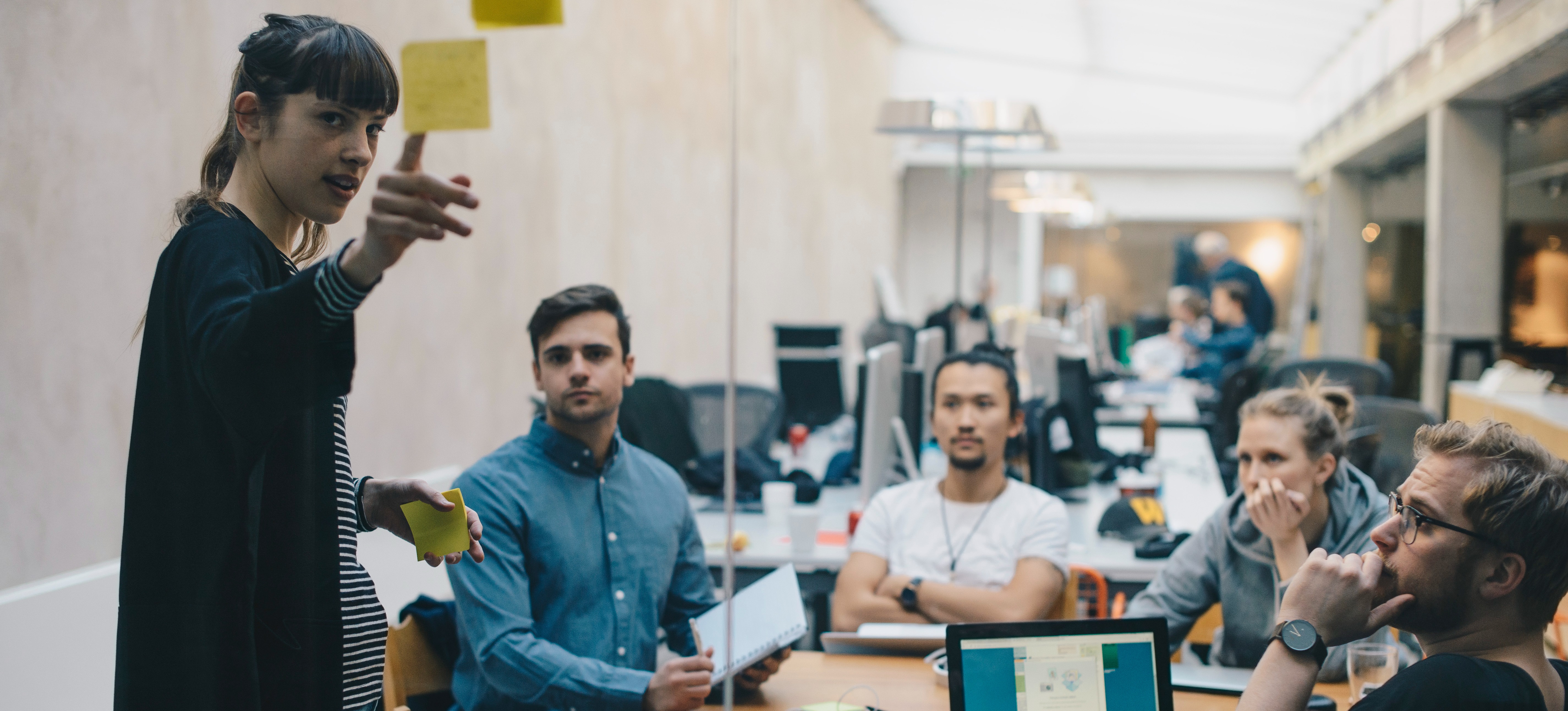 [Featured image]: A person with an IT project management certification uses sticky notes on a glass wall to guide their team.
