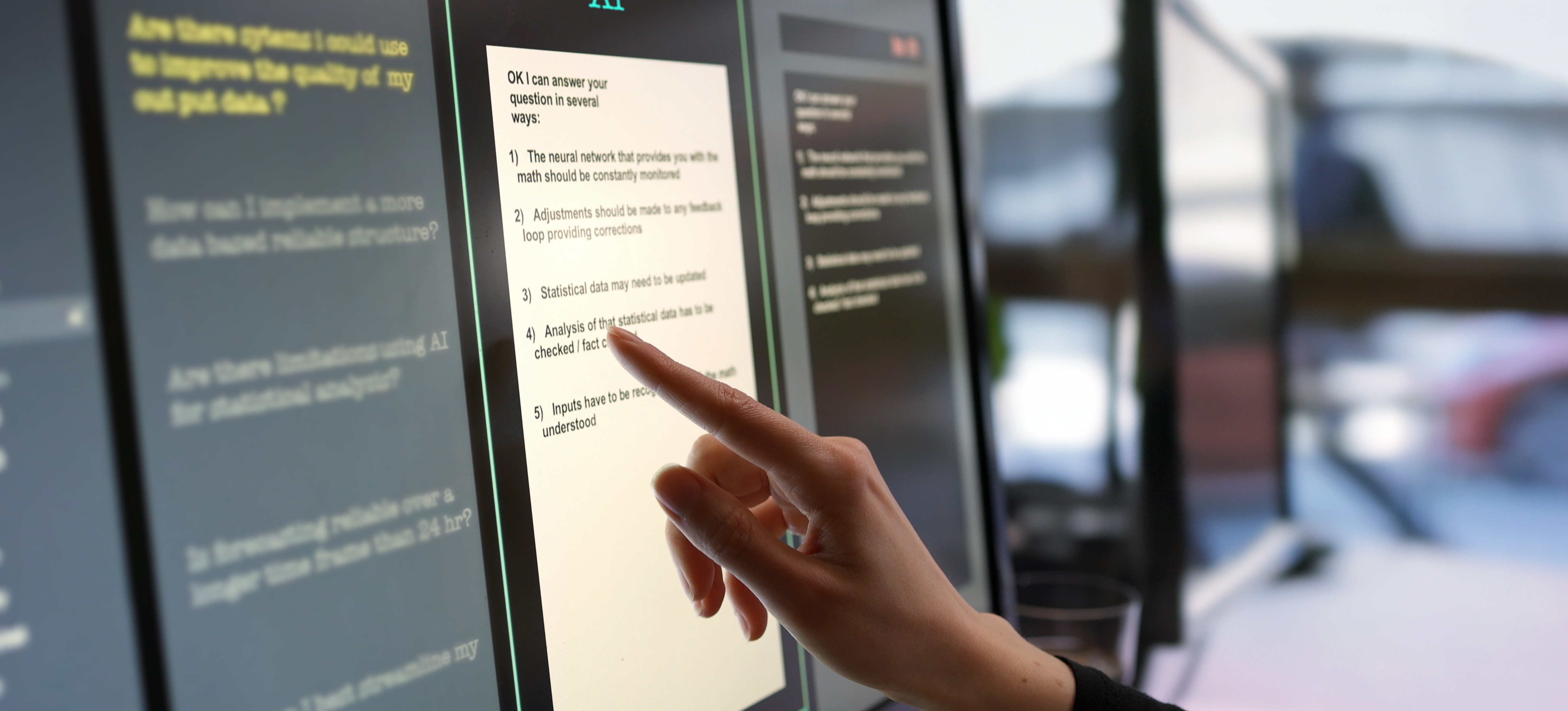 [Featured Image] A professional in a tech environment interacts with an on-device AI system, pointing at a computer screen that displays "Chatbot AI" on the interface.
