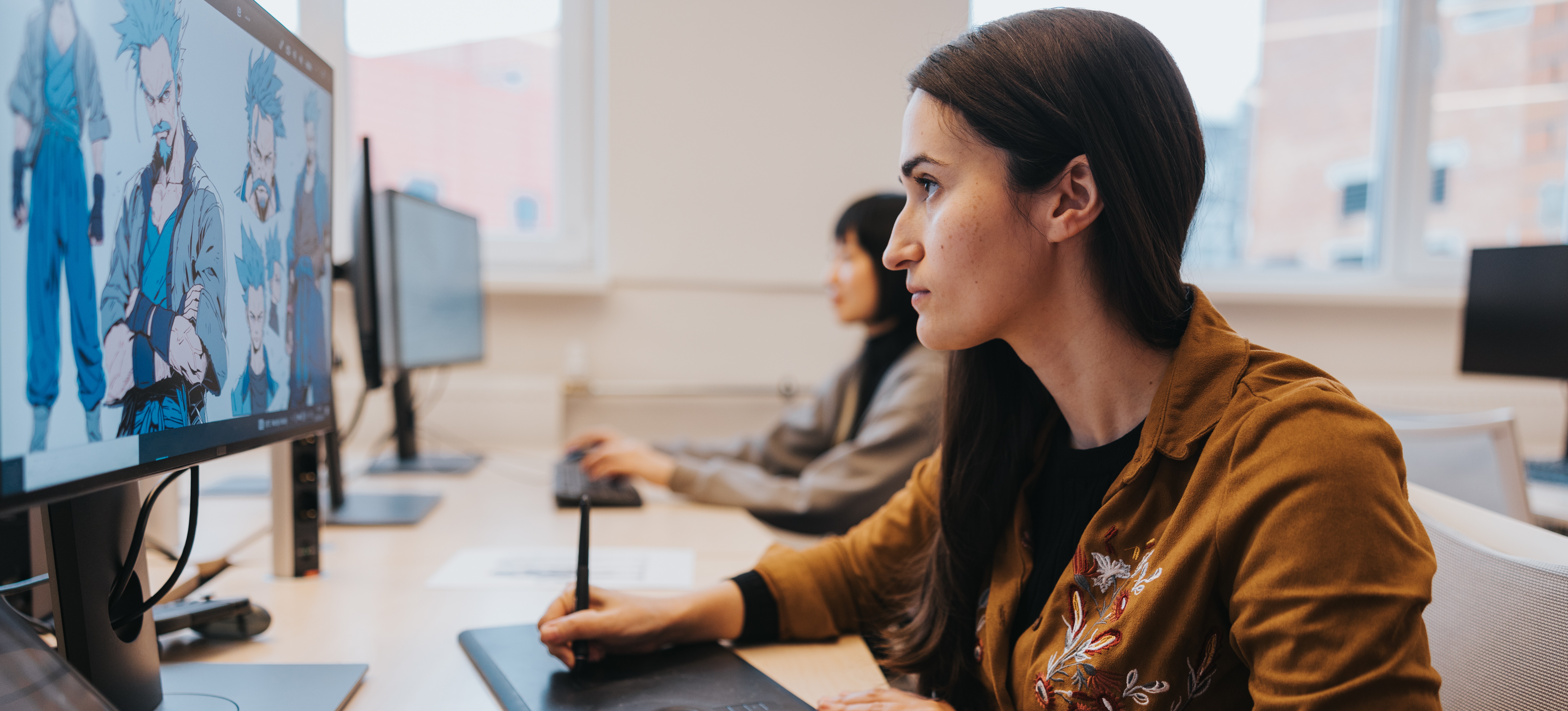 [Featured Image] A graphic artist, which is a digital content creator job, holds a stylus and creates an animated character on their computer screen.

