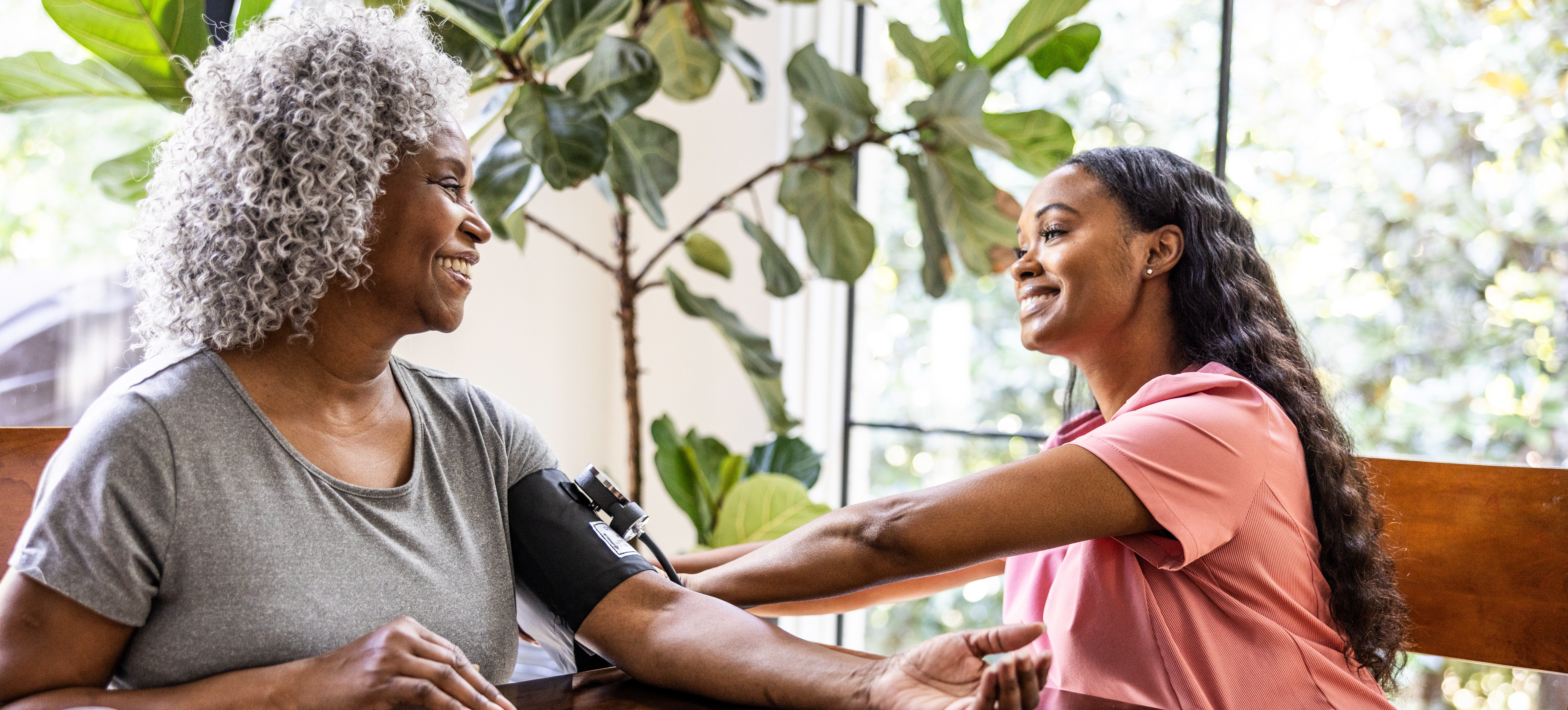 [Featured Image] Public health official taking the blood pressure of an elderly woman in her home.
