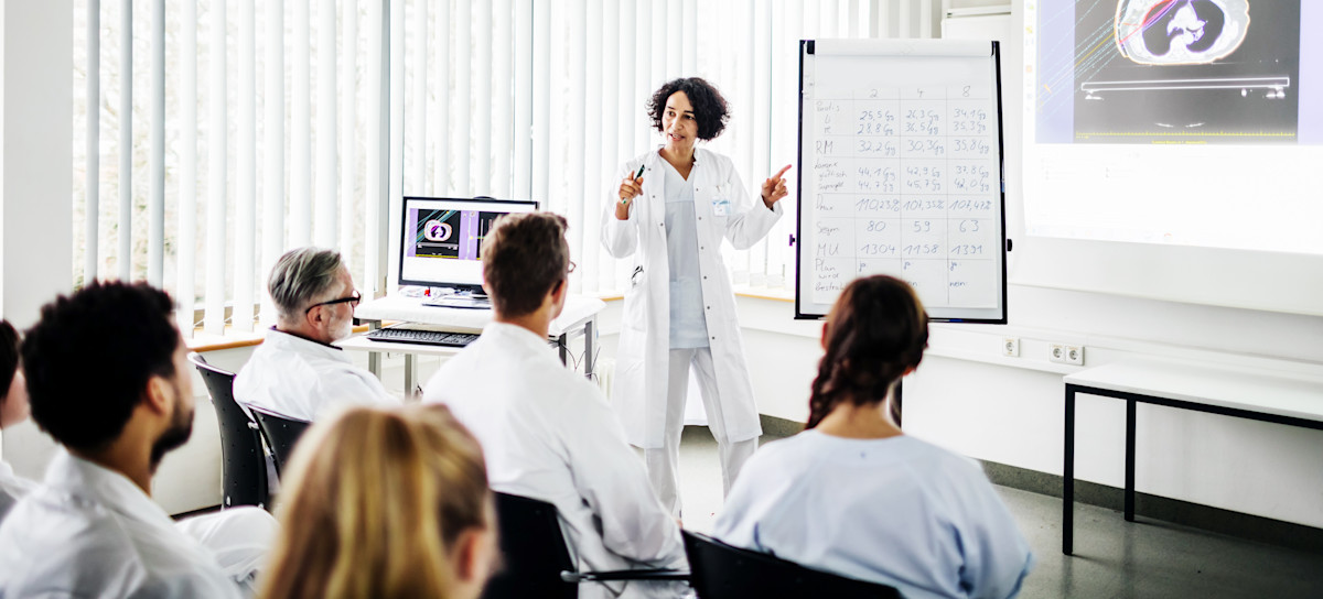 [Featured Image] An instructor explains to medical professionals how they will use augmented reality in health care as part of their job.