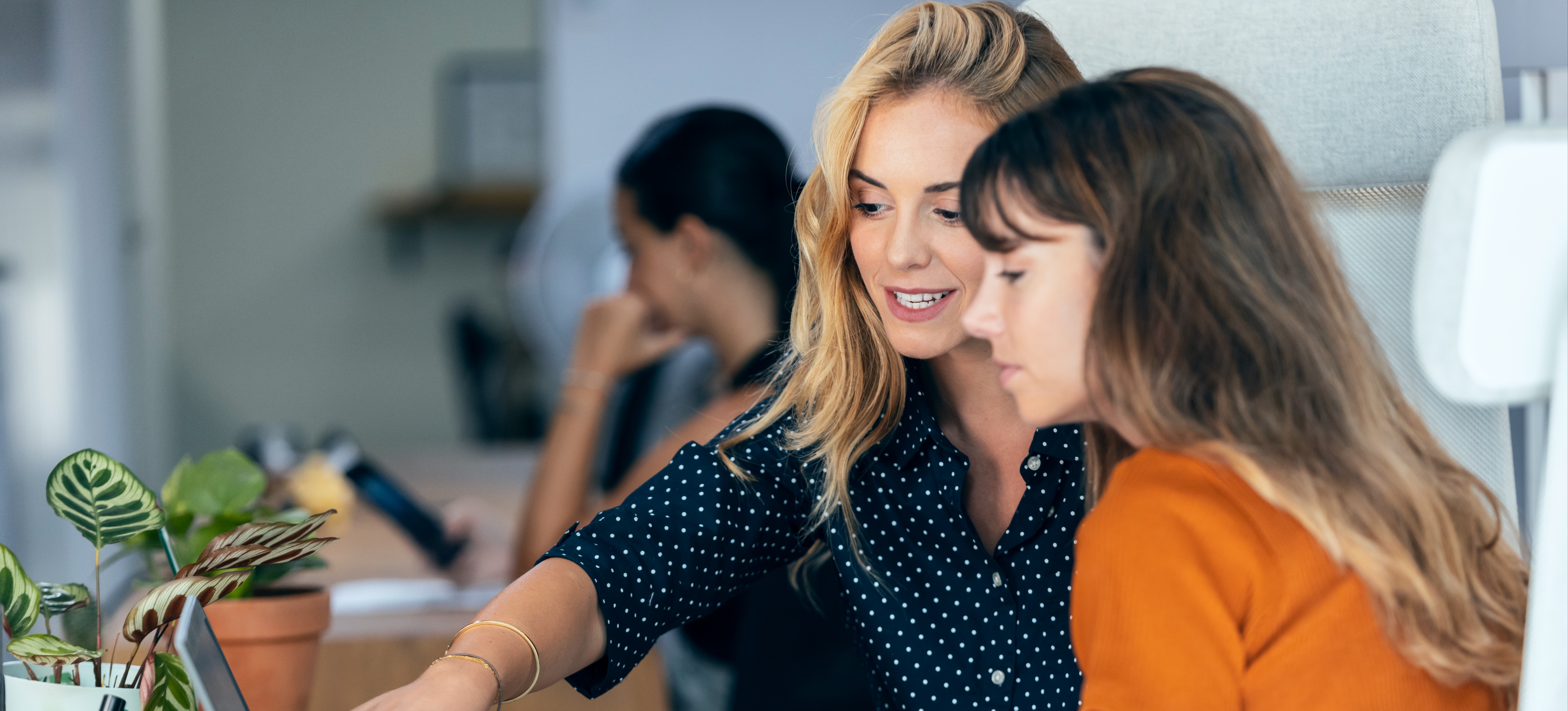 [Featured Image] Colleagues in a work environment, discussing and using cloud platforms, smiling and engaging with each other.
