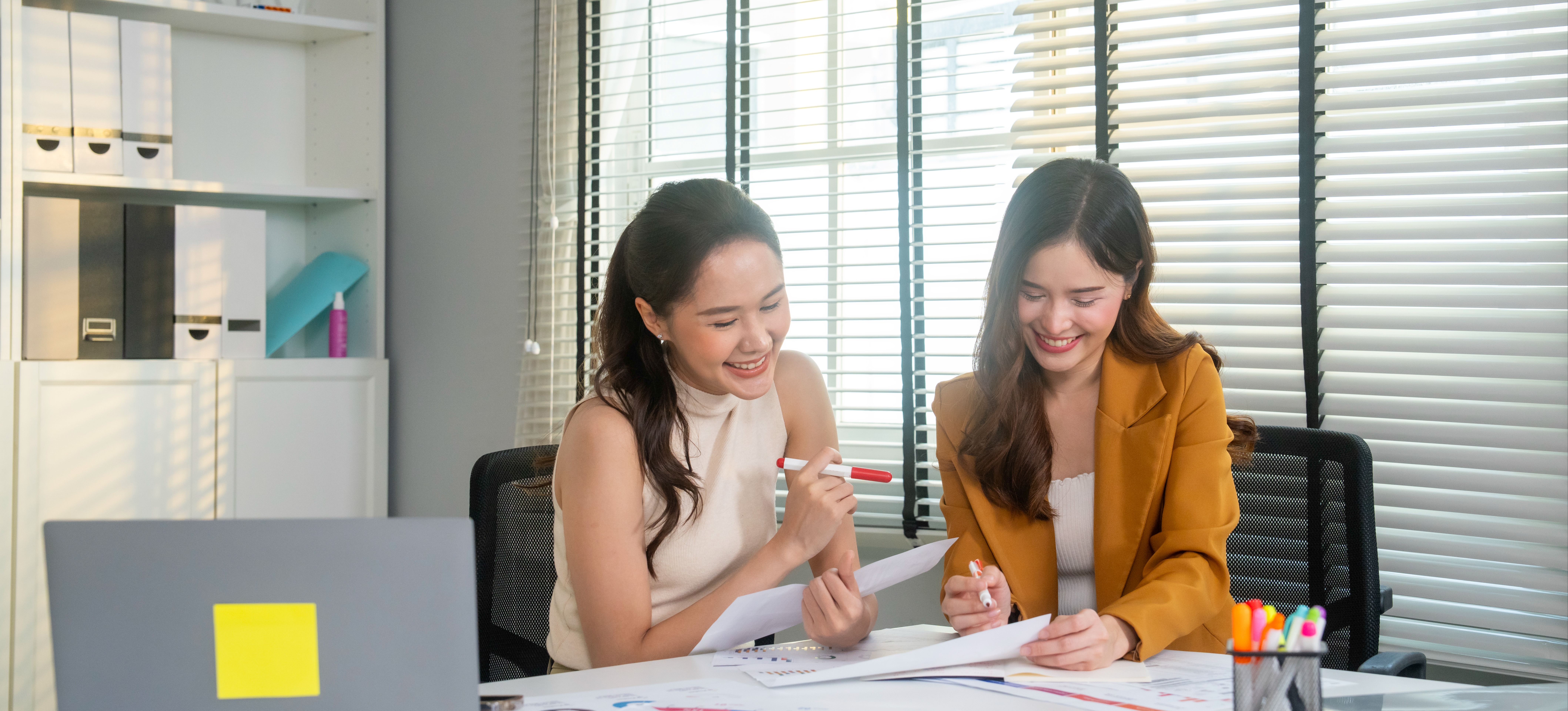 [Featured Image] Two marketing professionals meet to discuss their company's customer analytics. 