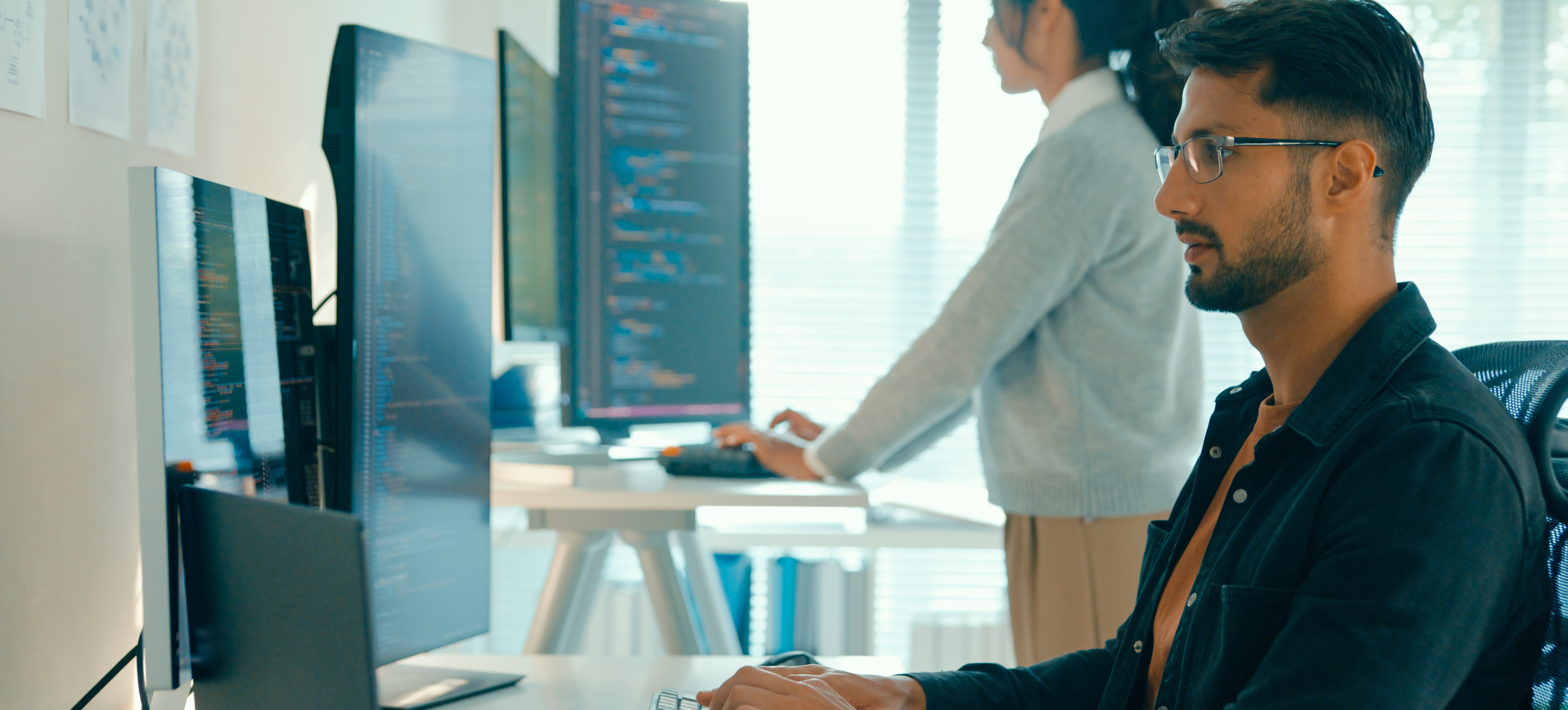 [Feature Image] Two solidity developers create smart contracts on computers while working for a blockchain company.
