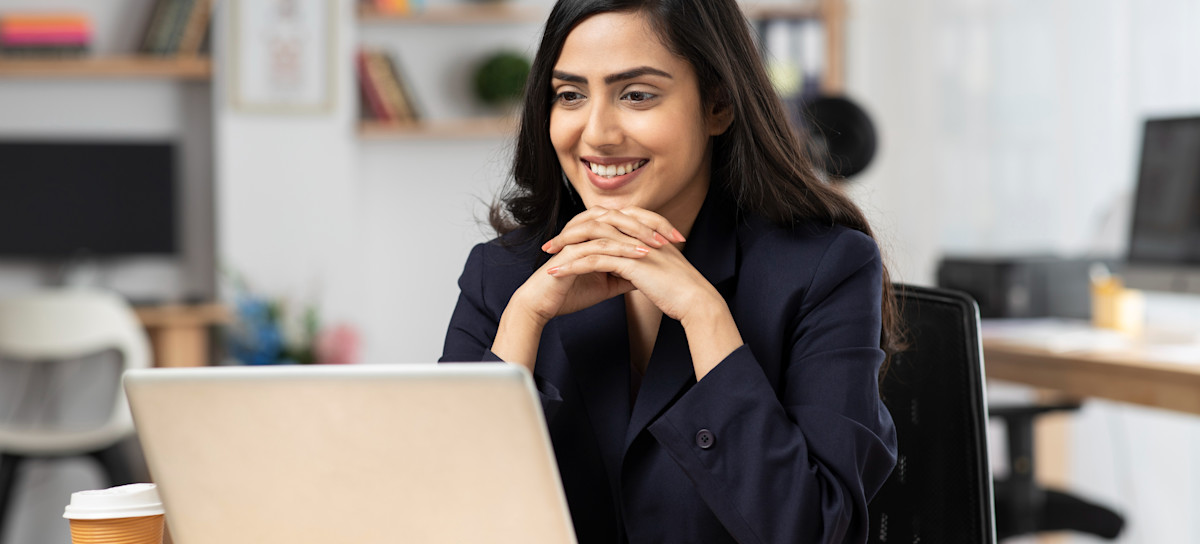 [Featured Image] A professional businessperson sits at their laptop in their office and works on a project involving machine learning in marketing. 
