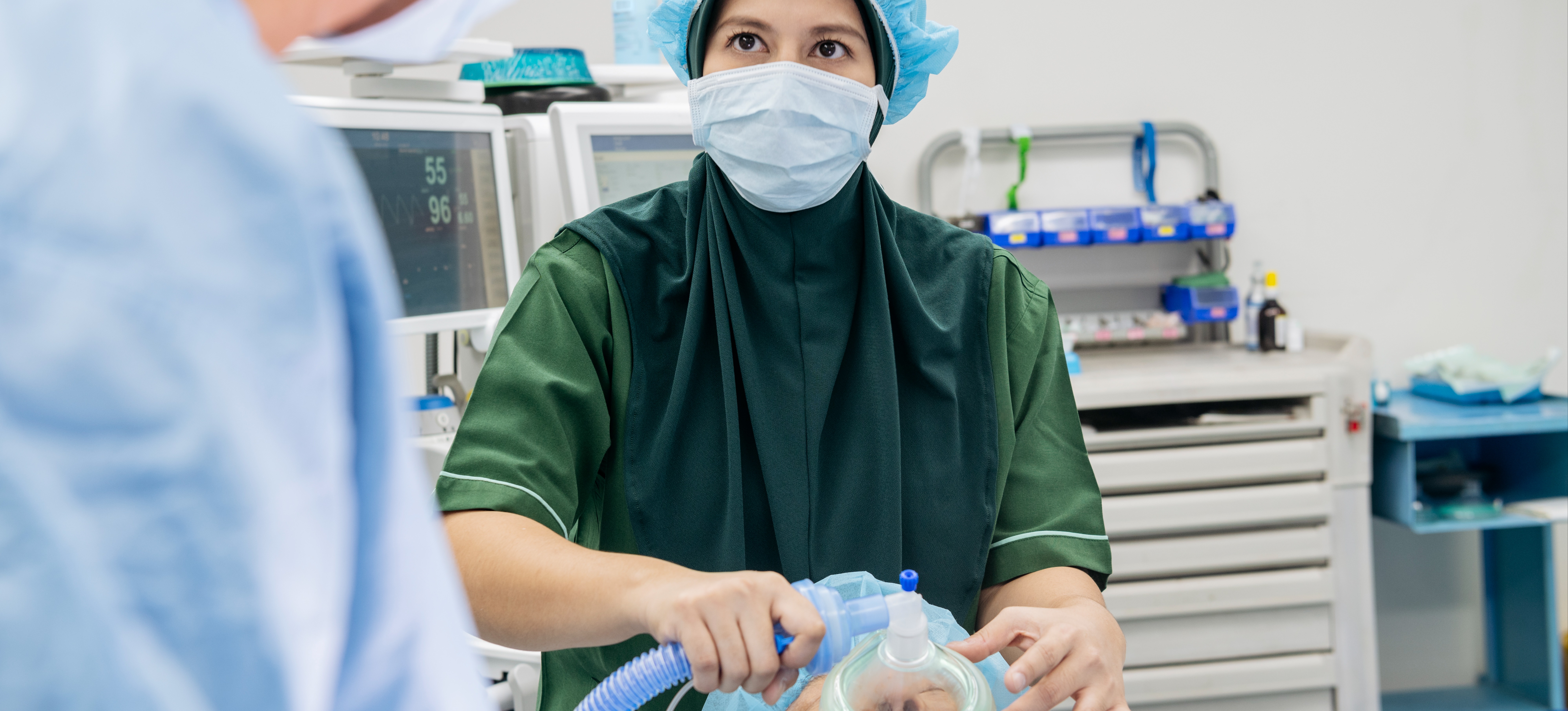[Featured Image] A nurse anesthetist cares for a patient in an operating room.