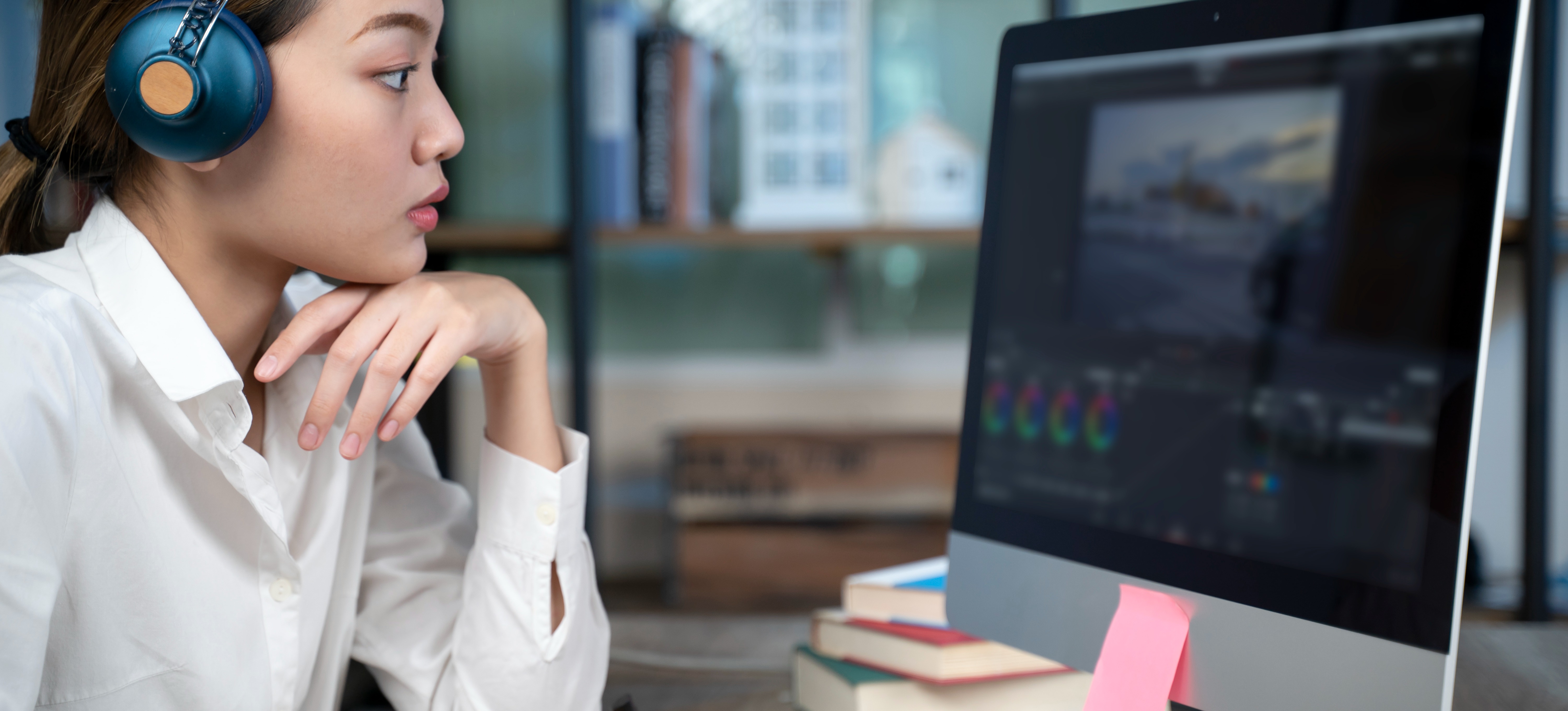 [Featured image] A person learning video editing on a computer with headphones on. 