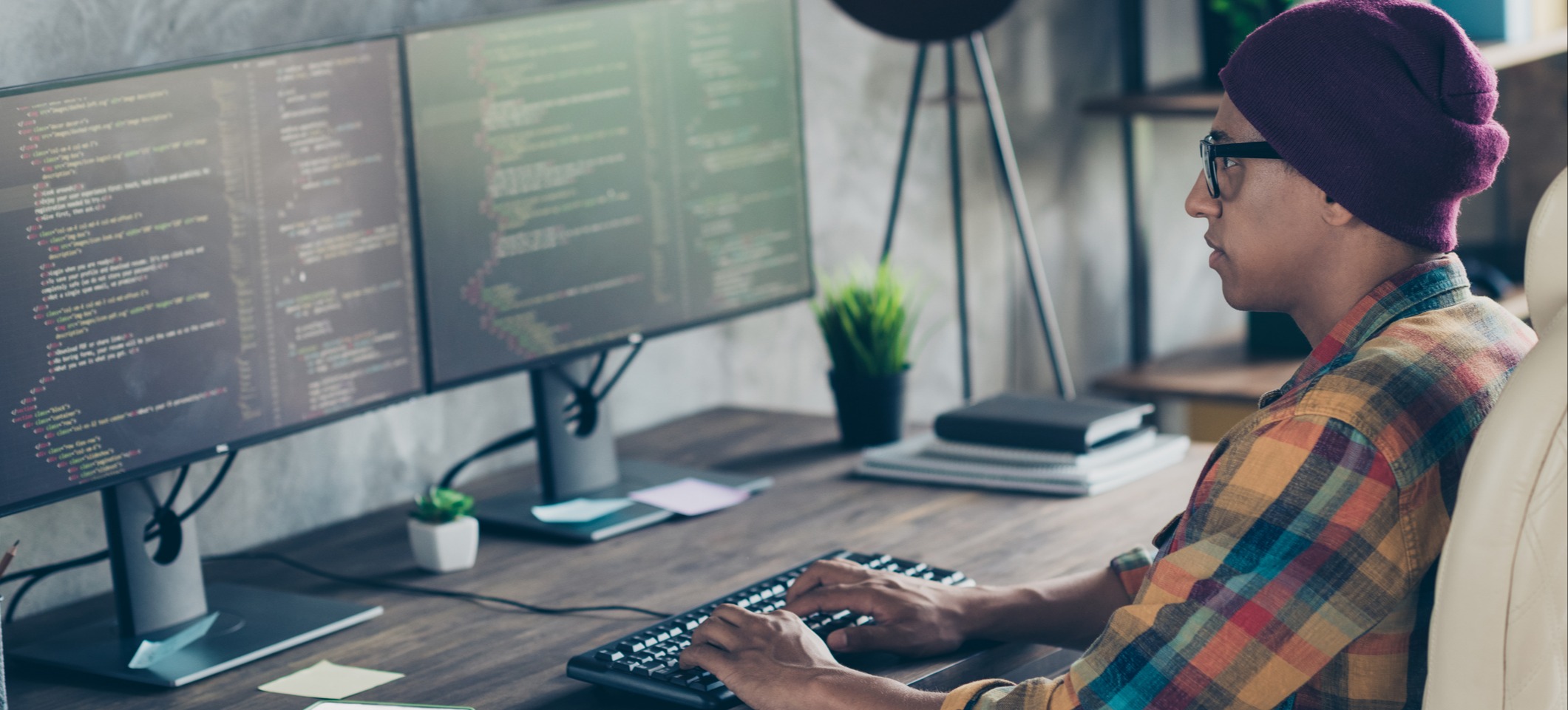 [Featured Image] A web developer works with React Native or React.js as they code on a computer with two monitors in a home office.
