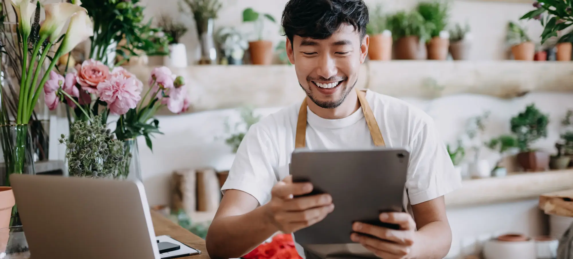 [Featured image] A person who just started his own business selling plants looks over sales records on a tablet.