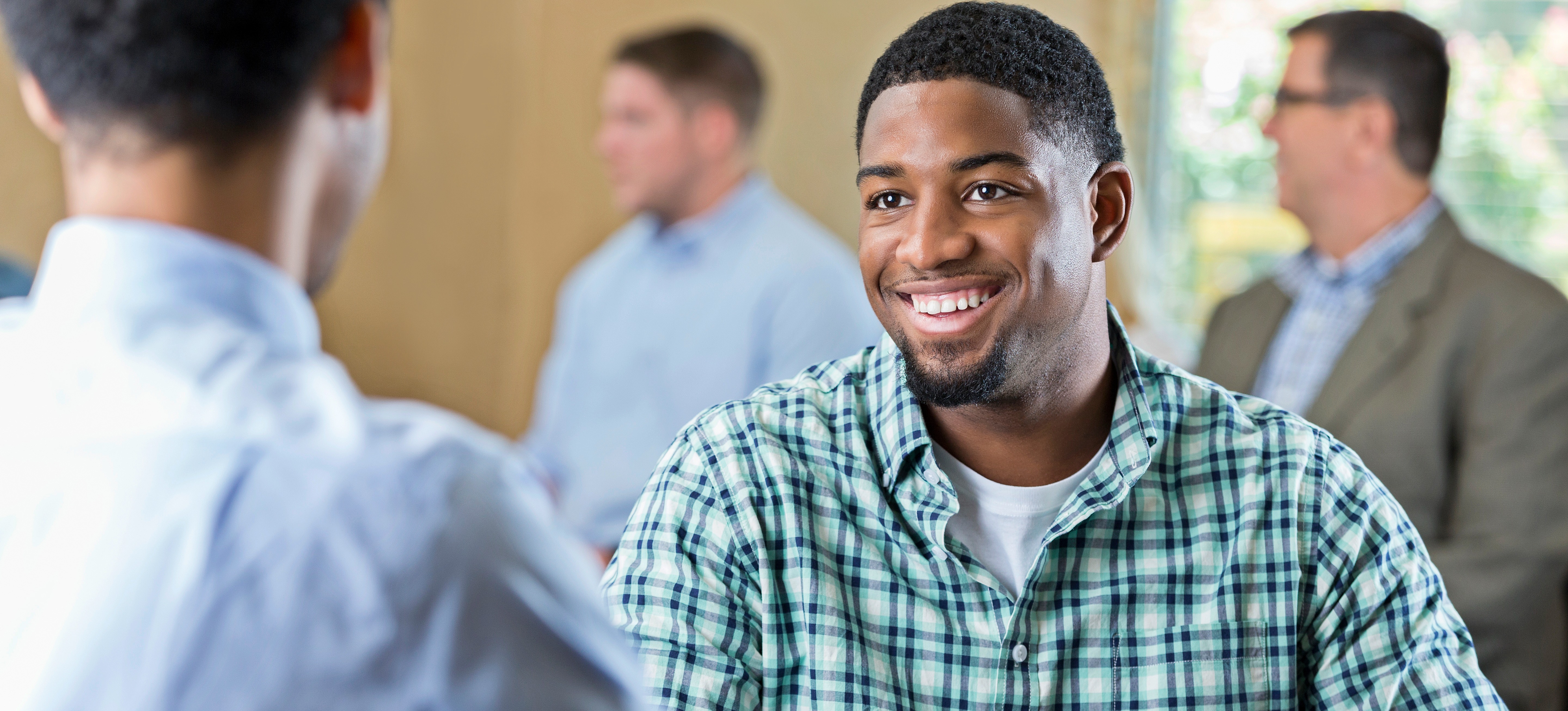[Featured Image] A smiling student sits across a table from a college admissions officer as they answer college interview questions as part of the admittance process.