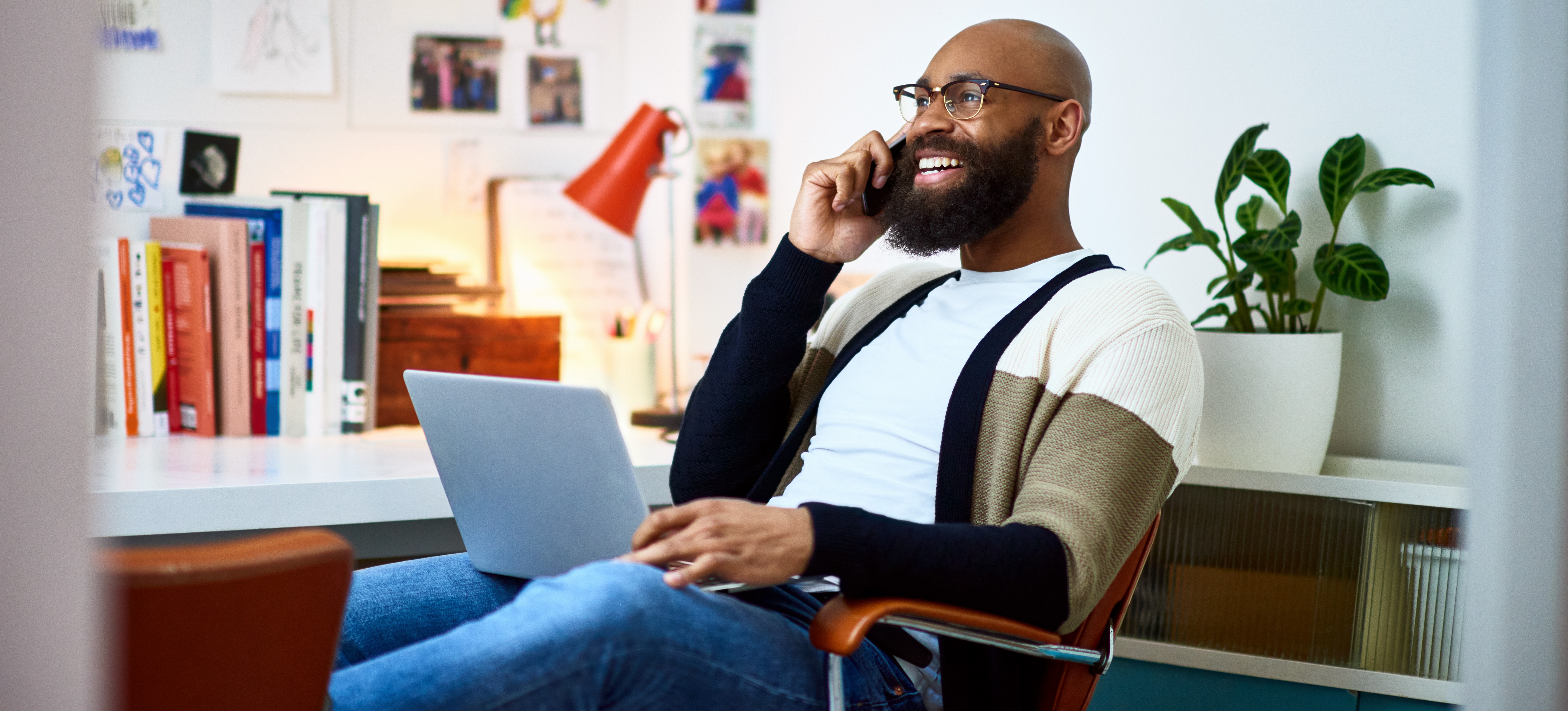 [Featured Image] A person sits at their desk with a laptop on their knees while answering phone interview questions.