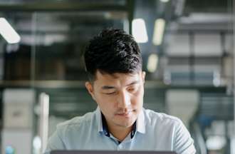 [Featured image] A male, wearing a white shirt, is working on his laptop, as he works on a marketing strategy for his marTech team. 