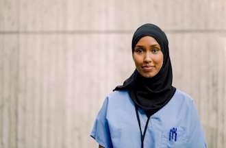 [Featured image] A licensed practical nurse smiles while wearing blue scrubs.