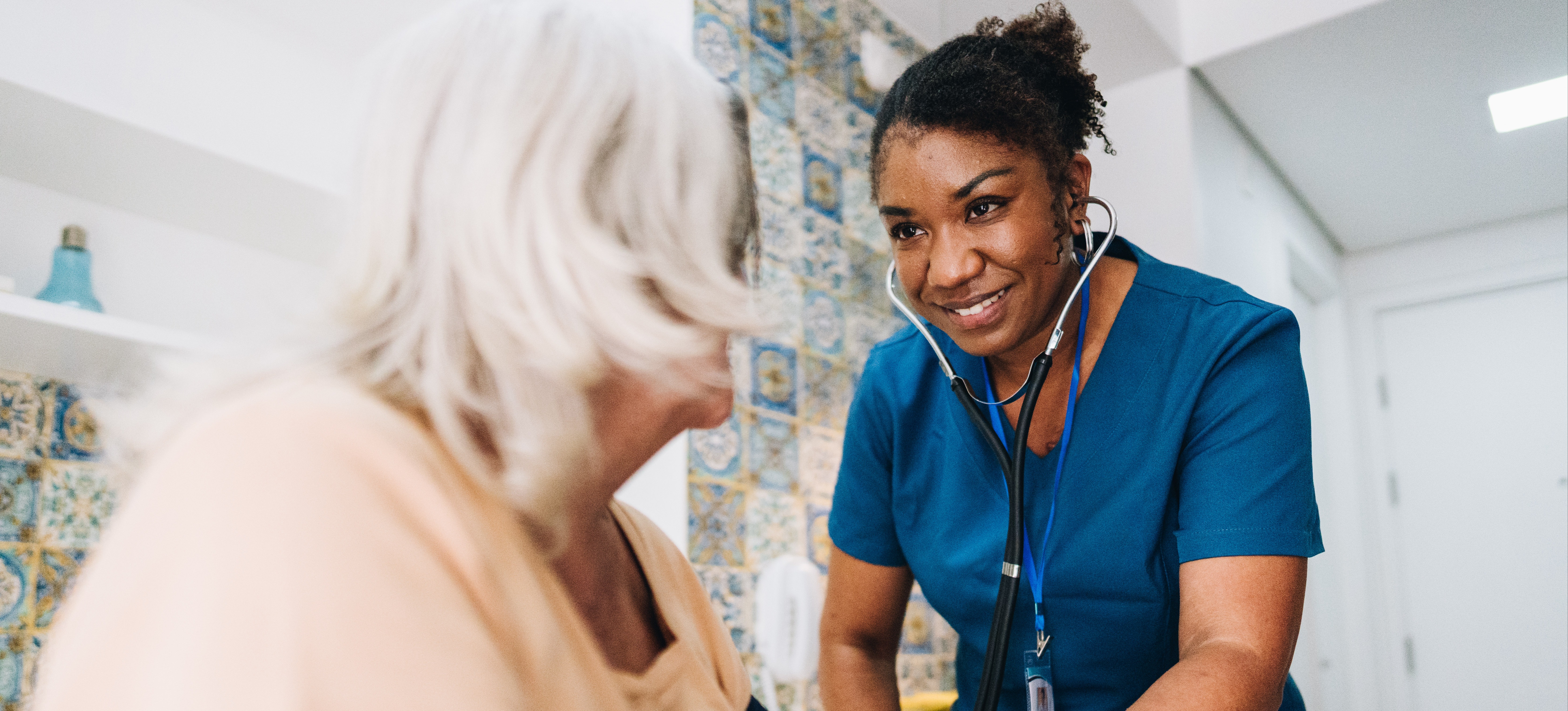 [Featured Image] A licensed practical nurse takes the blood pressure of a patient in their home.
