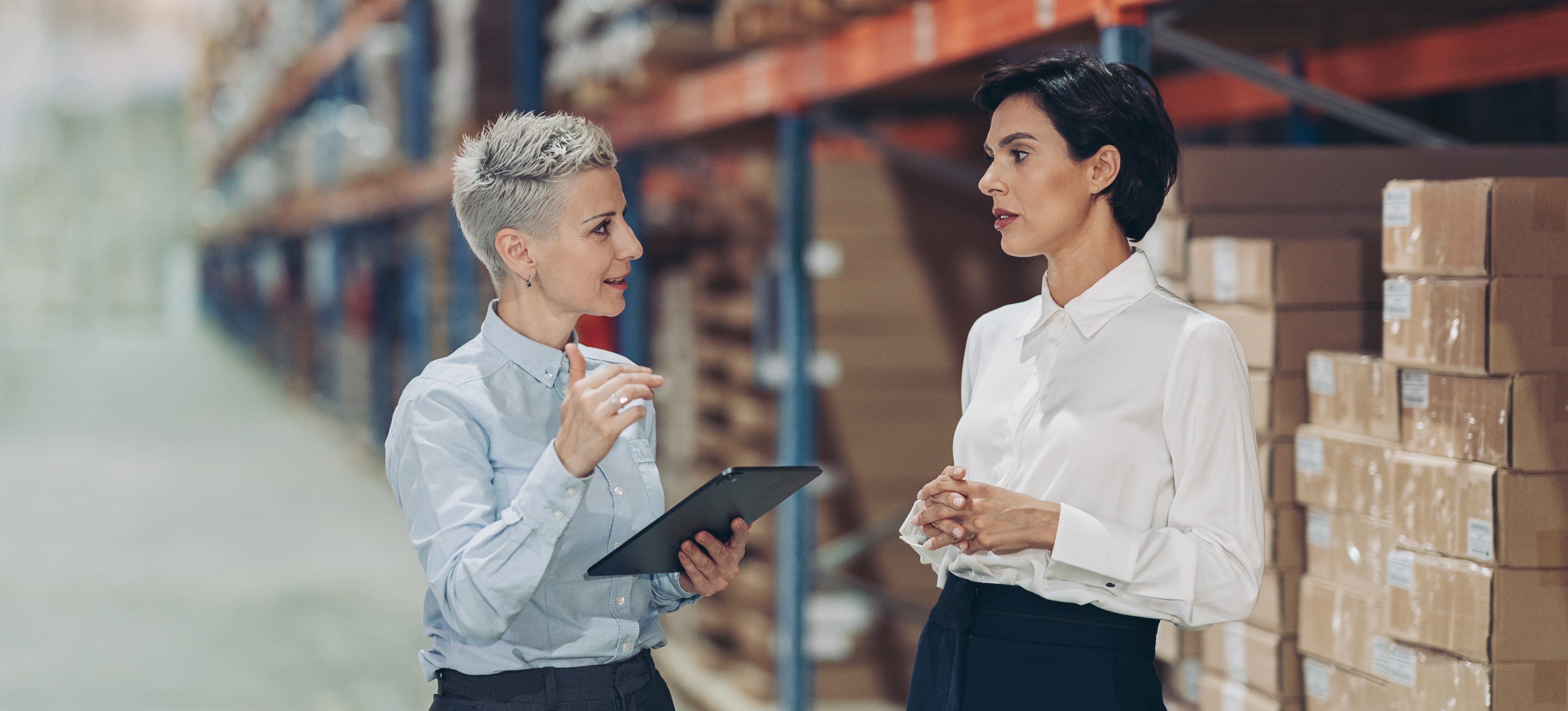 [Featured Image] A business manager is giving a raise to the company's product specialist in a warehouse.