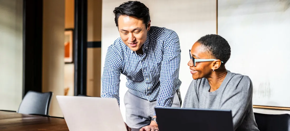 [Featured image] Two business professionals review the results after one learned how to use ChatGPT for competitor analysis and created a report for their next meeting. 
