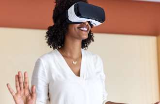 [Featured Image] A smiling woman uses a VR headset in a brightly colored room.