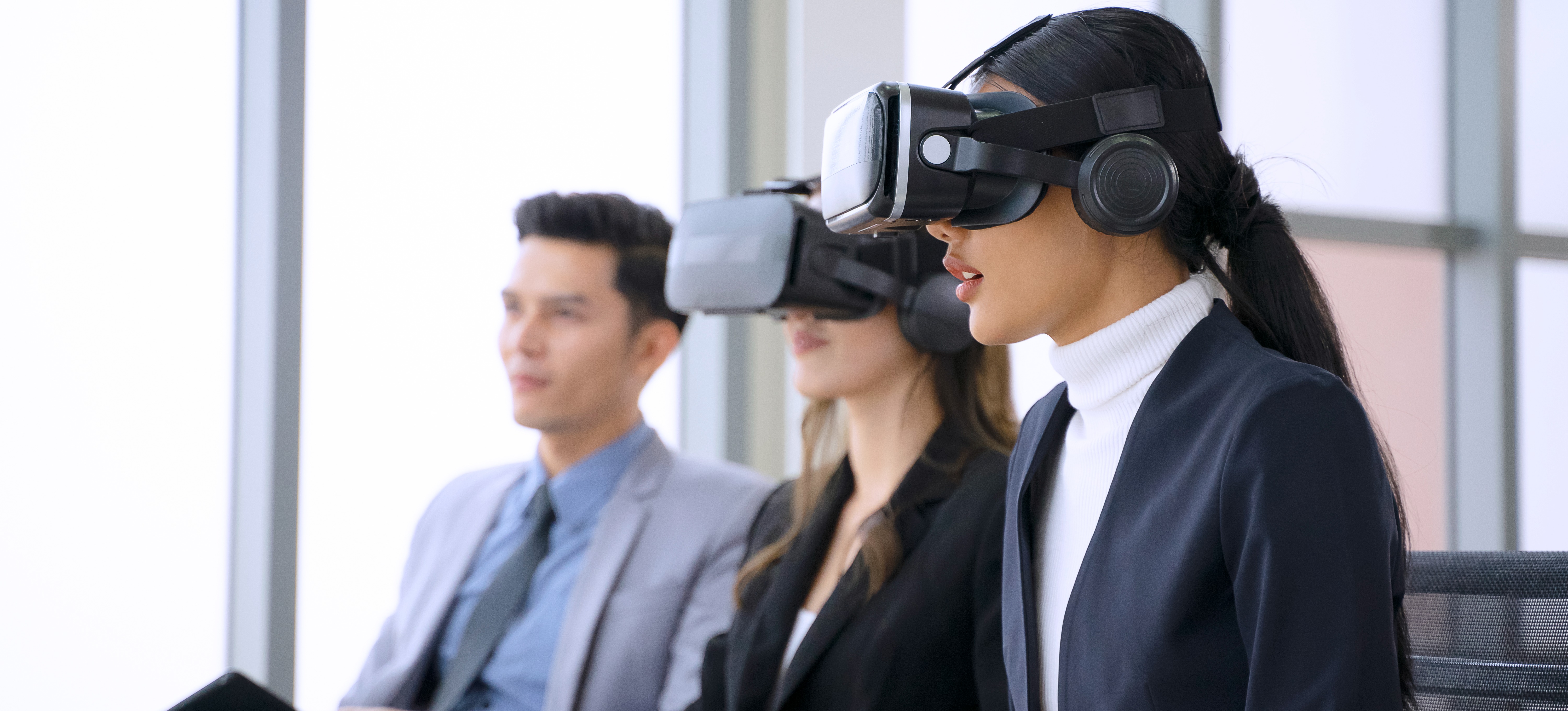 [Featured Image] Two people are wearing VR headsets during a meeting discussing implementing metaverse technology into their business dealings.