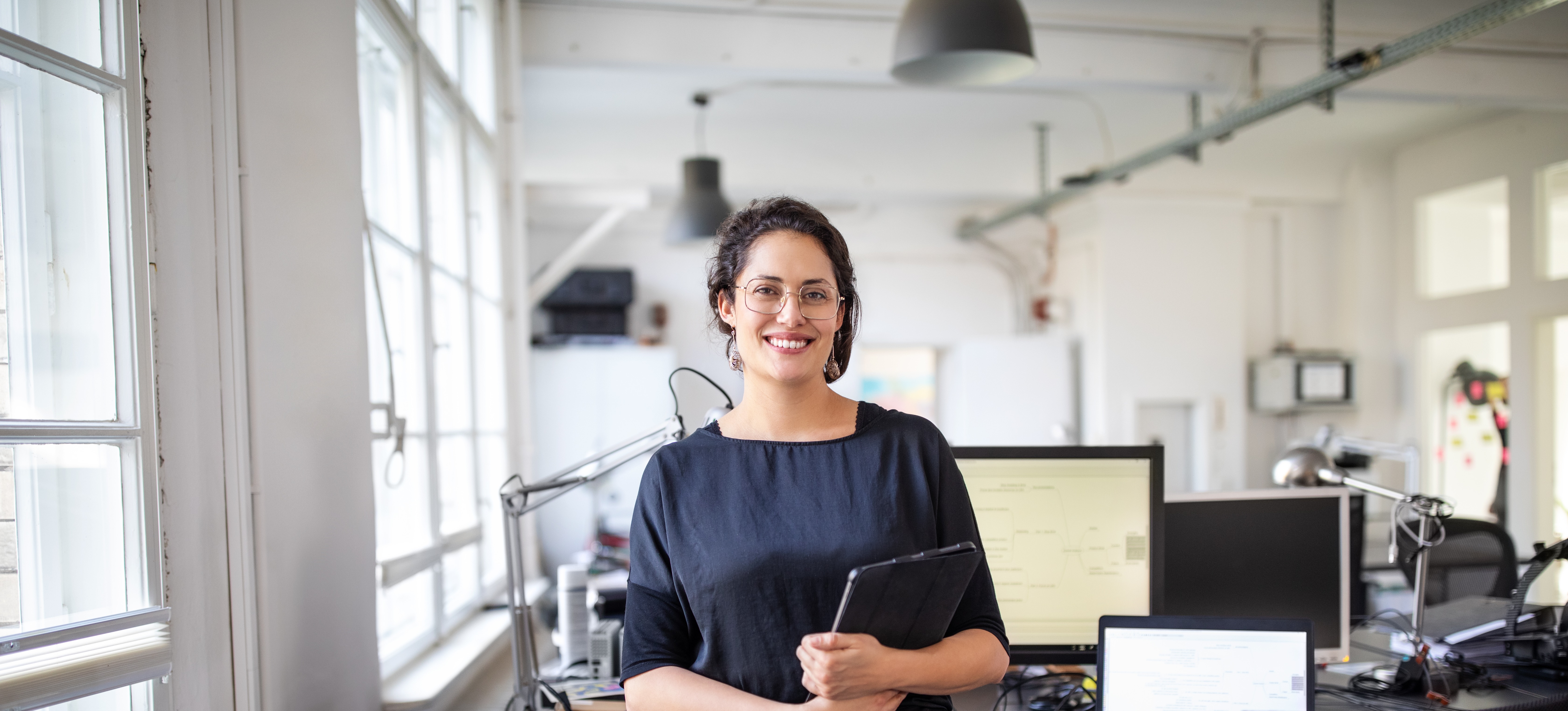 [Featured Image] A professional in a black top stands in an office.