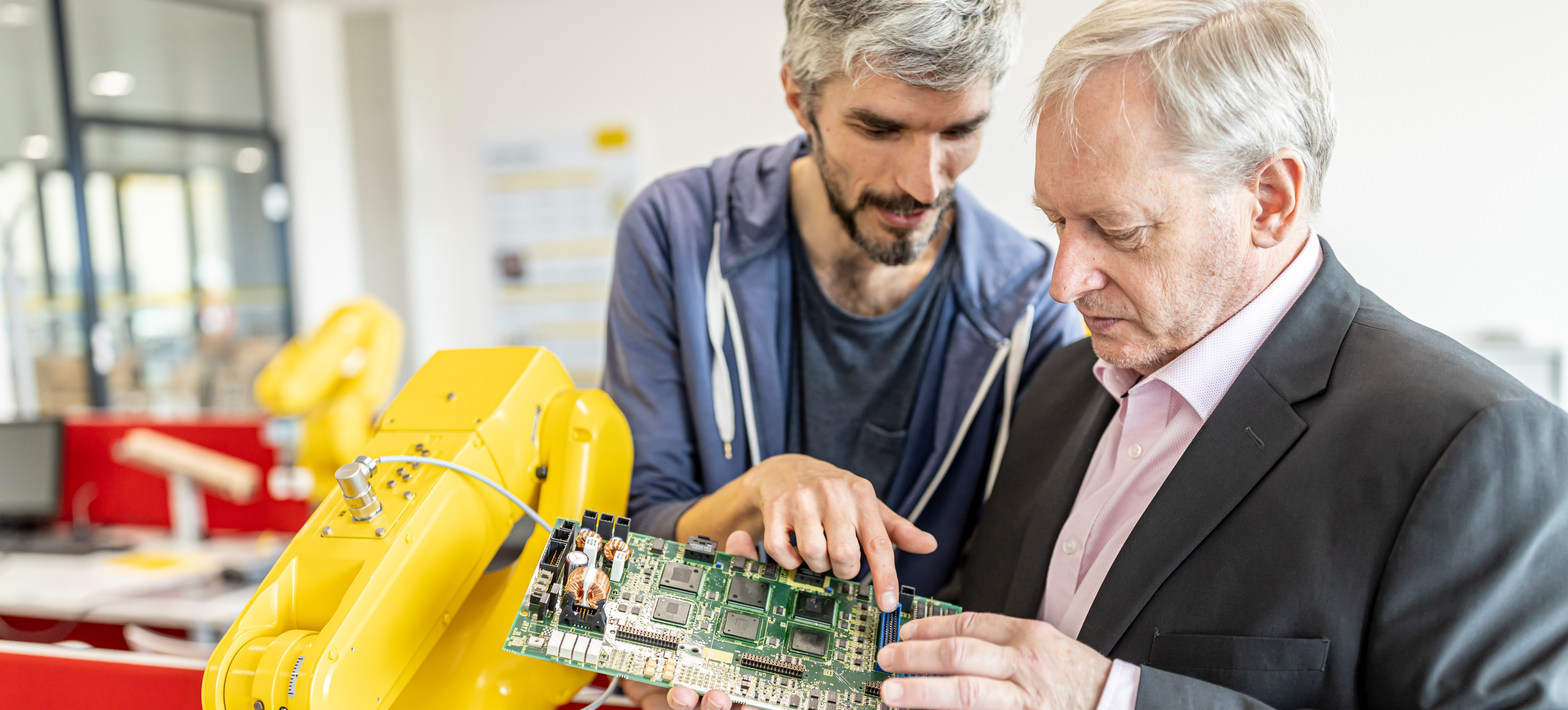[Image en vedette] Deux professionnels examinent la carte mère d'un robot.