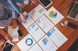 [Featured Image] A group of coworkers sit around a conference table, analyzing the best way to begin their business optimization strategy. 