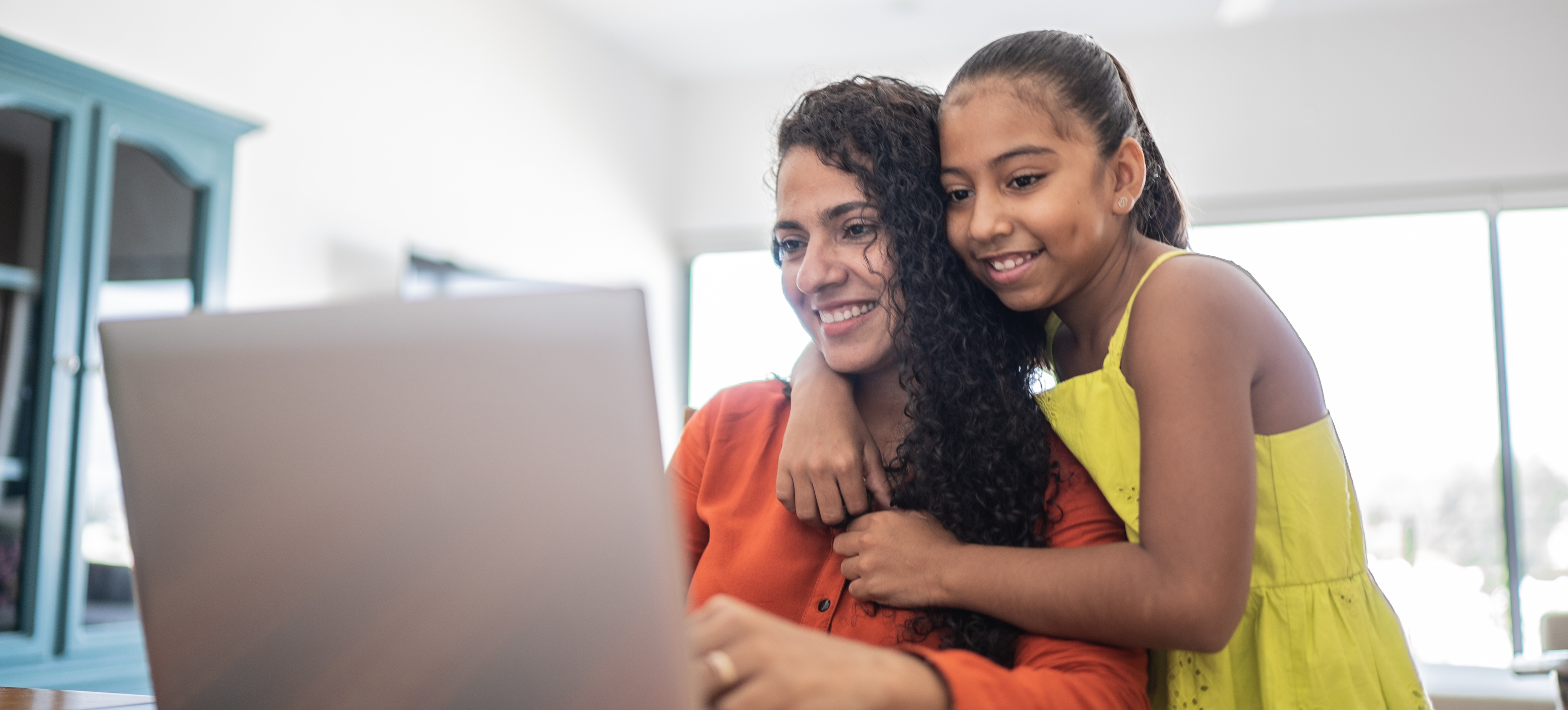 [Image en vedette] Une apprenante travaillant à domicile reçoit un câlin de sa fille alors qu'elles surfent sur Internet en toute confiance, sachant qu'elles ont mis en place un pare-feu proxy efficace. 
