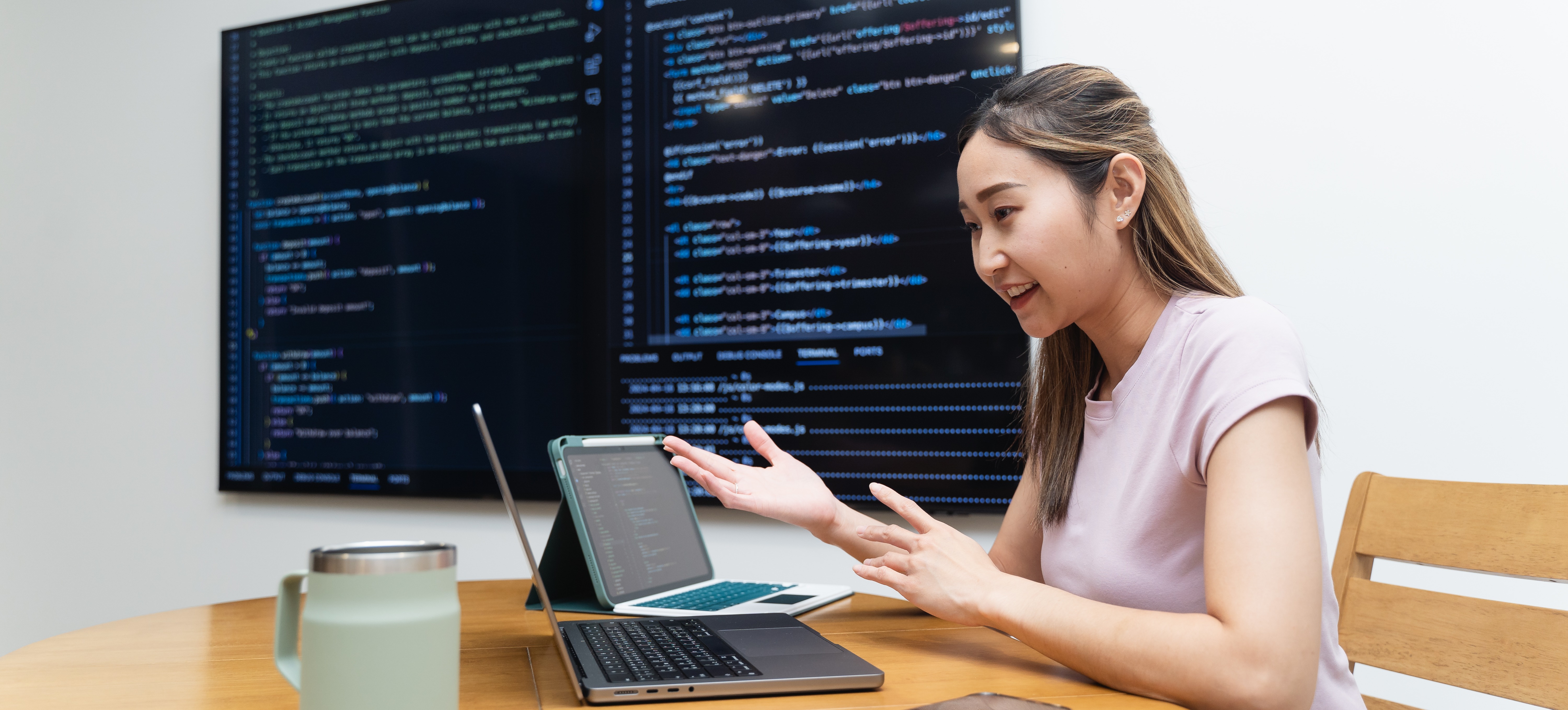 [Featured Image] A Python developer is explaining the Python job description to someone on her laptop using her tablet and computer monitor in the background.
