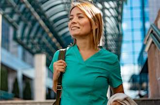 [Featured image] A travel nurse in teal scrubs walks through an airport.