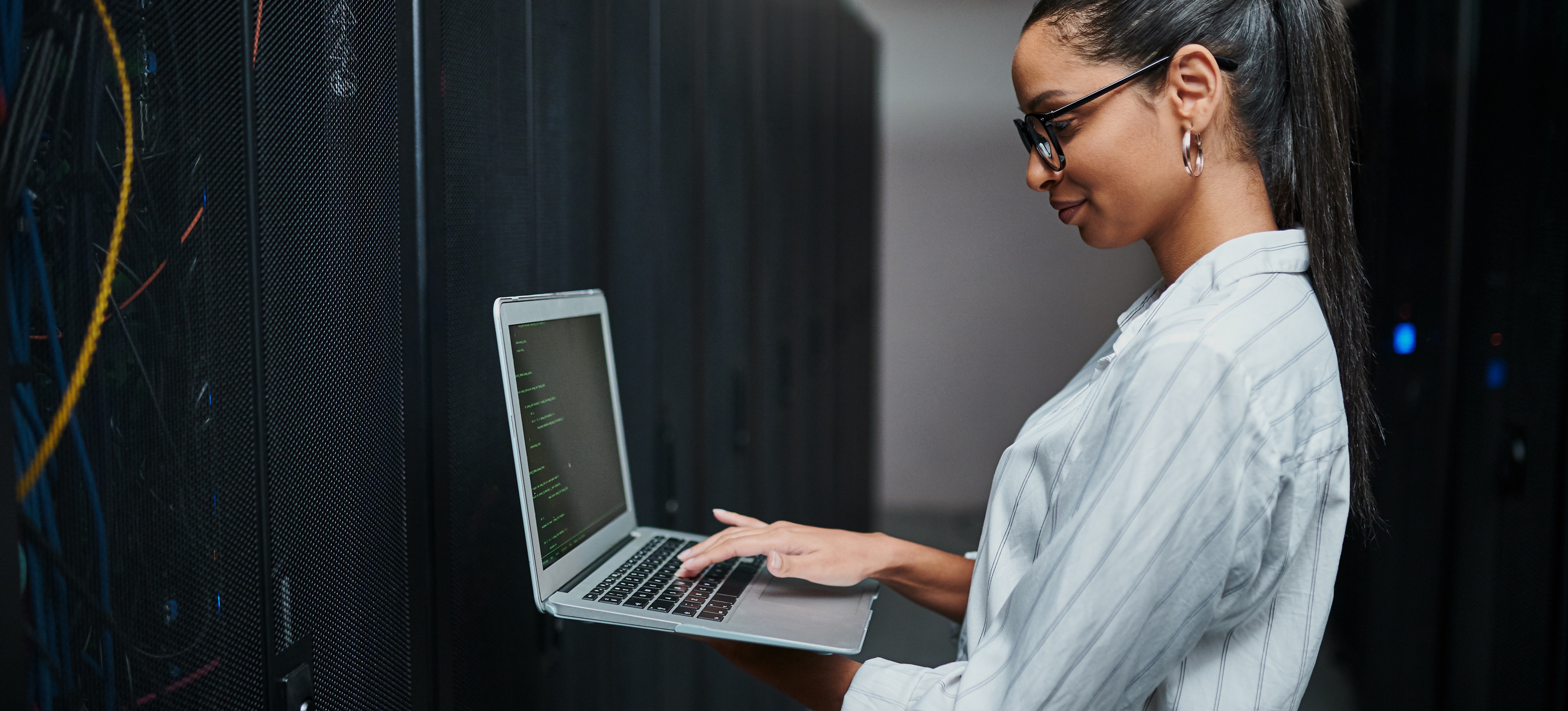 [Hauptbild] Eine Frau arbeitet an einem Laptop in einem Rechenzentrum, in dem Daten gespeichert sind, auf die Benutzer über Gigabit-Ethernet zugreifen können.