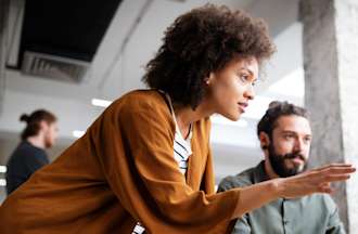 [Featured image] A woman in DevOps points to her colleague's computer screen.