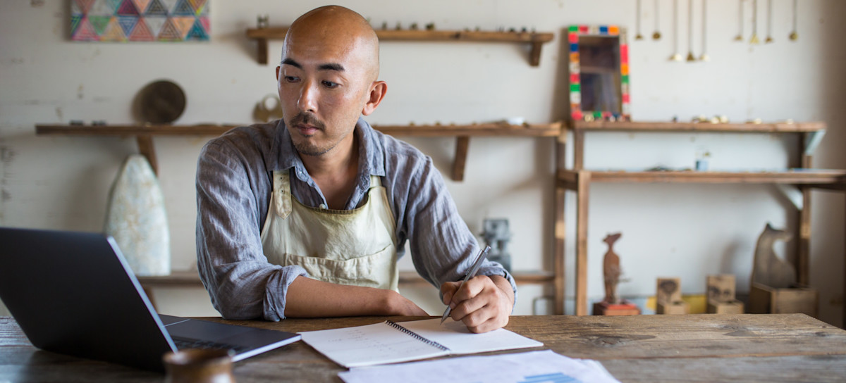 [Featured Image] A business owner sits at a desk, calculating the business’s accounting profit.
