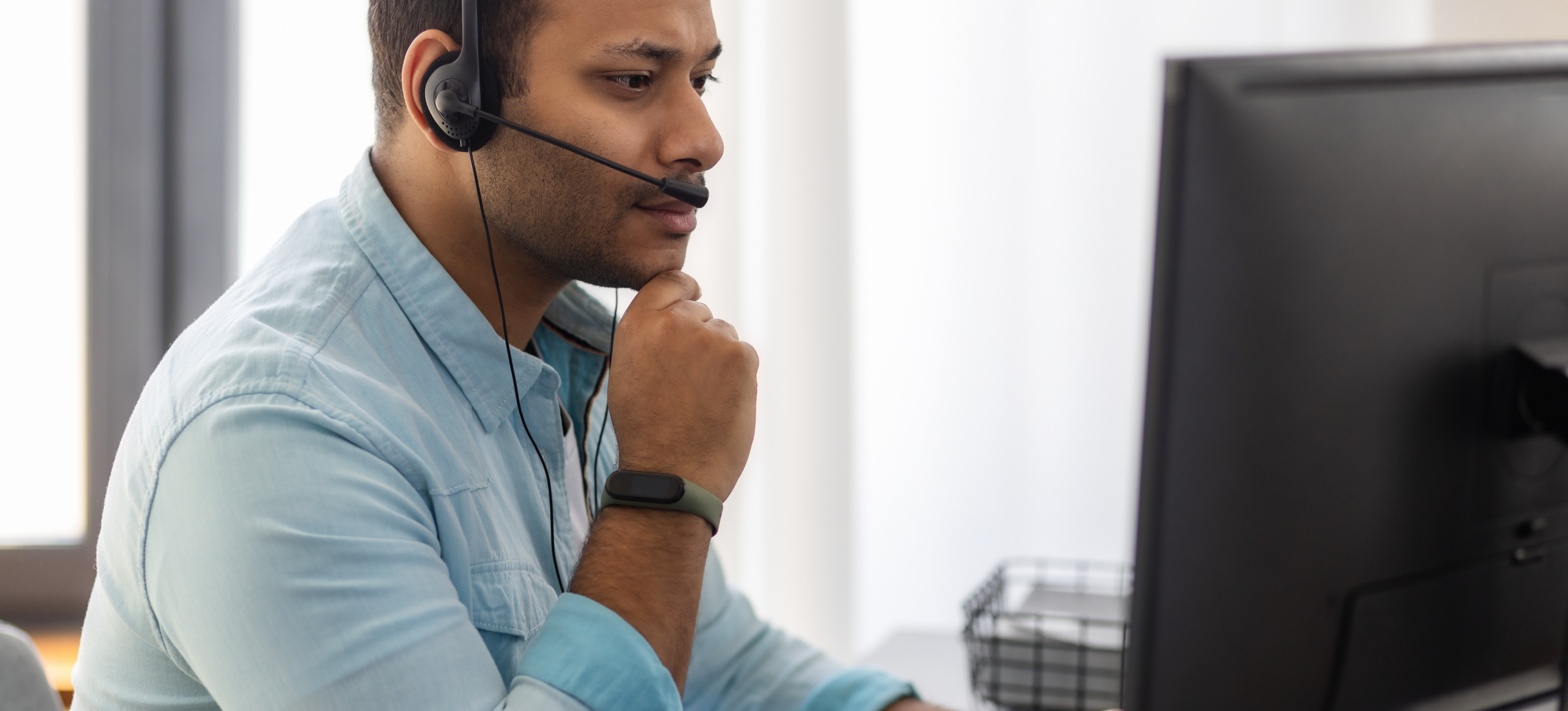 [Featured Image]: A man sits in front of a computer monitoring the system for common types of cyberattacks.
