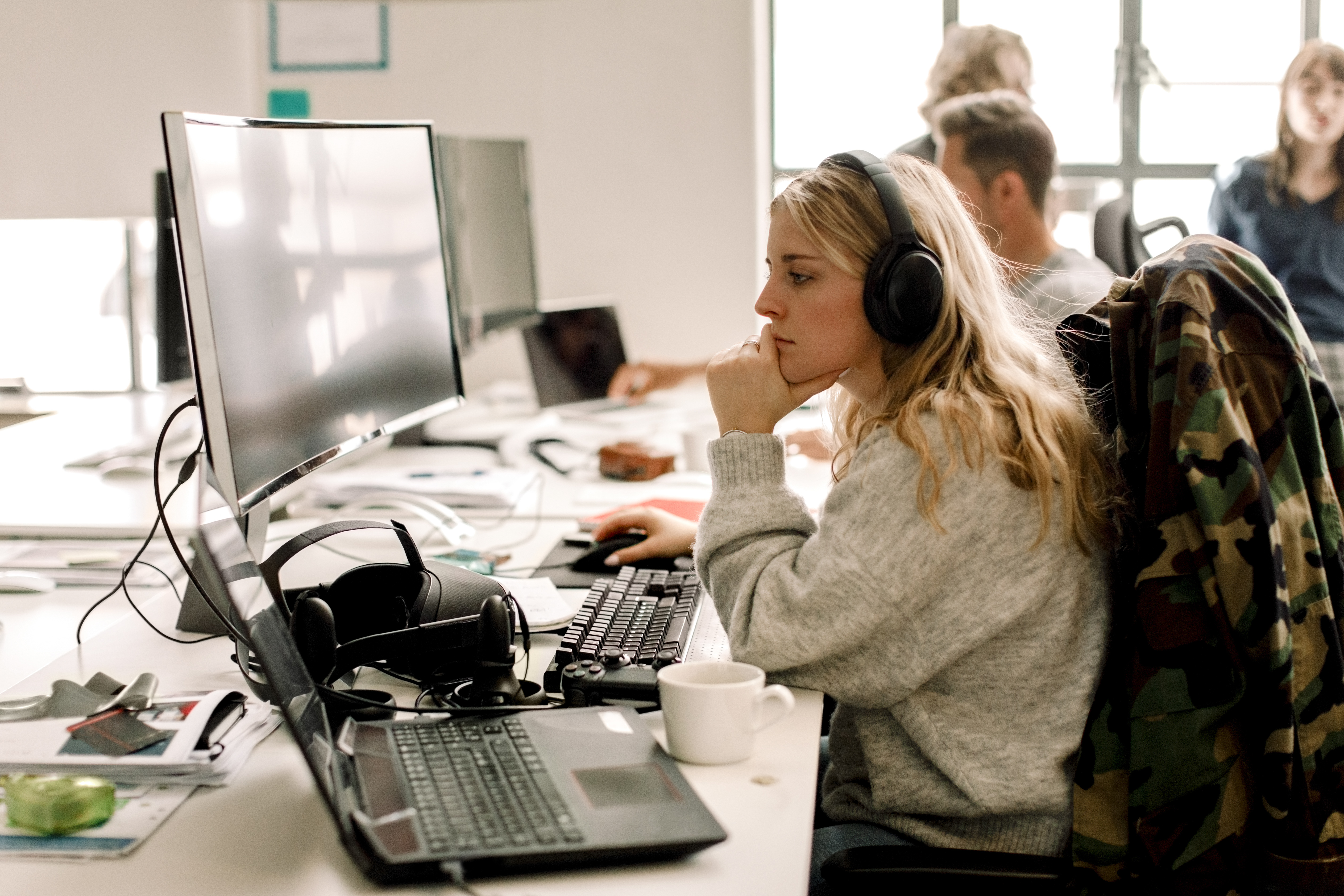 [Featured image] A vigilant woman, wearing a jacket and headphones, closely monitors her computer screen for signs of cyber threats.