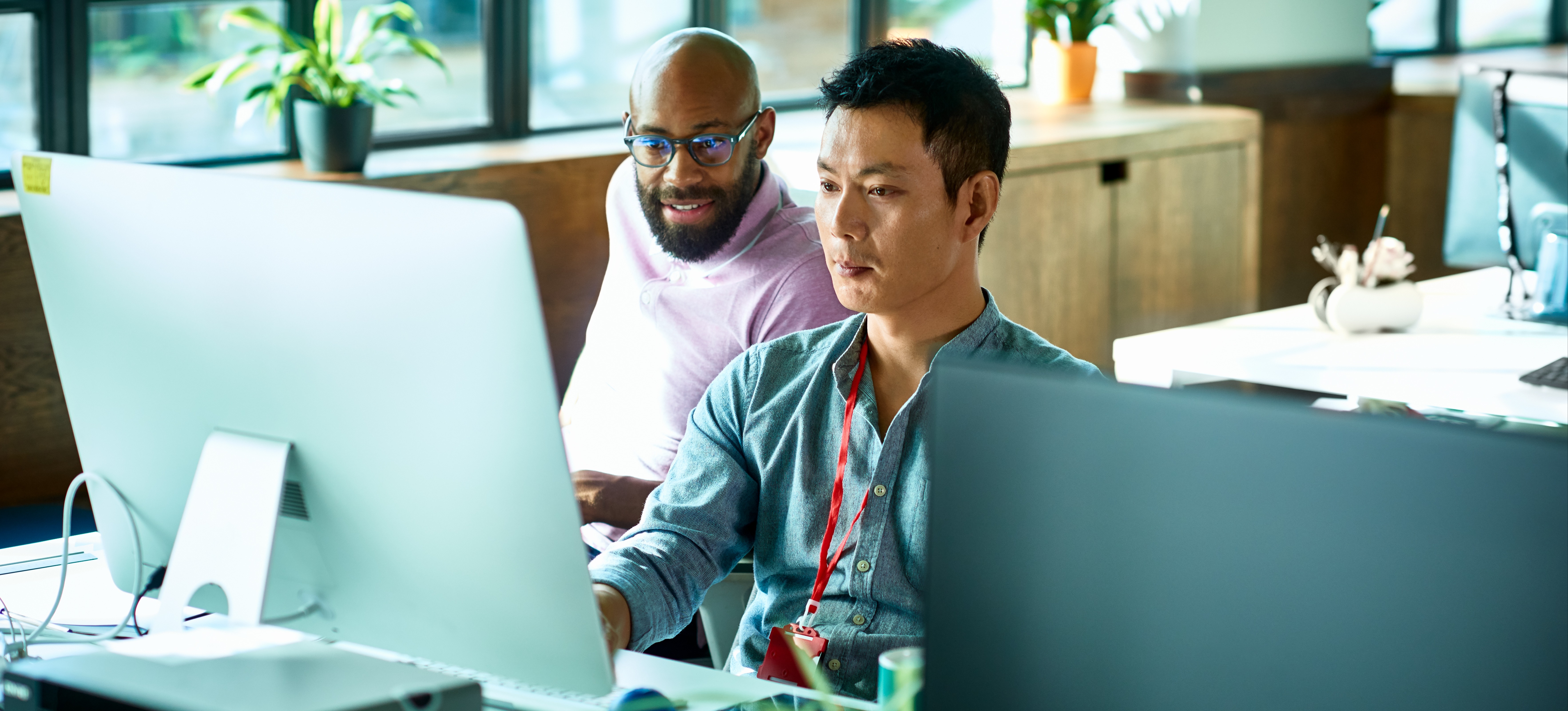 [Featured image]: Two NLP researchers seated behind a computer, using latent space while developing a model.
