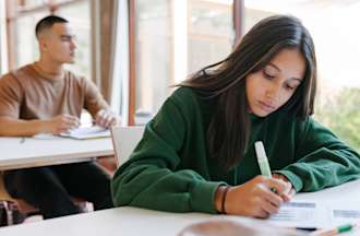A candidate sitting at her desk concentrating during an entrance exam.