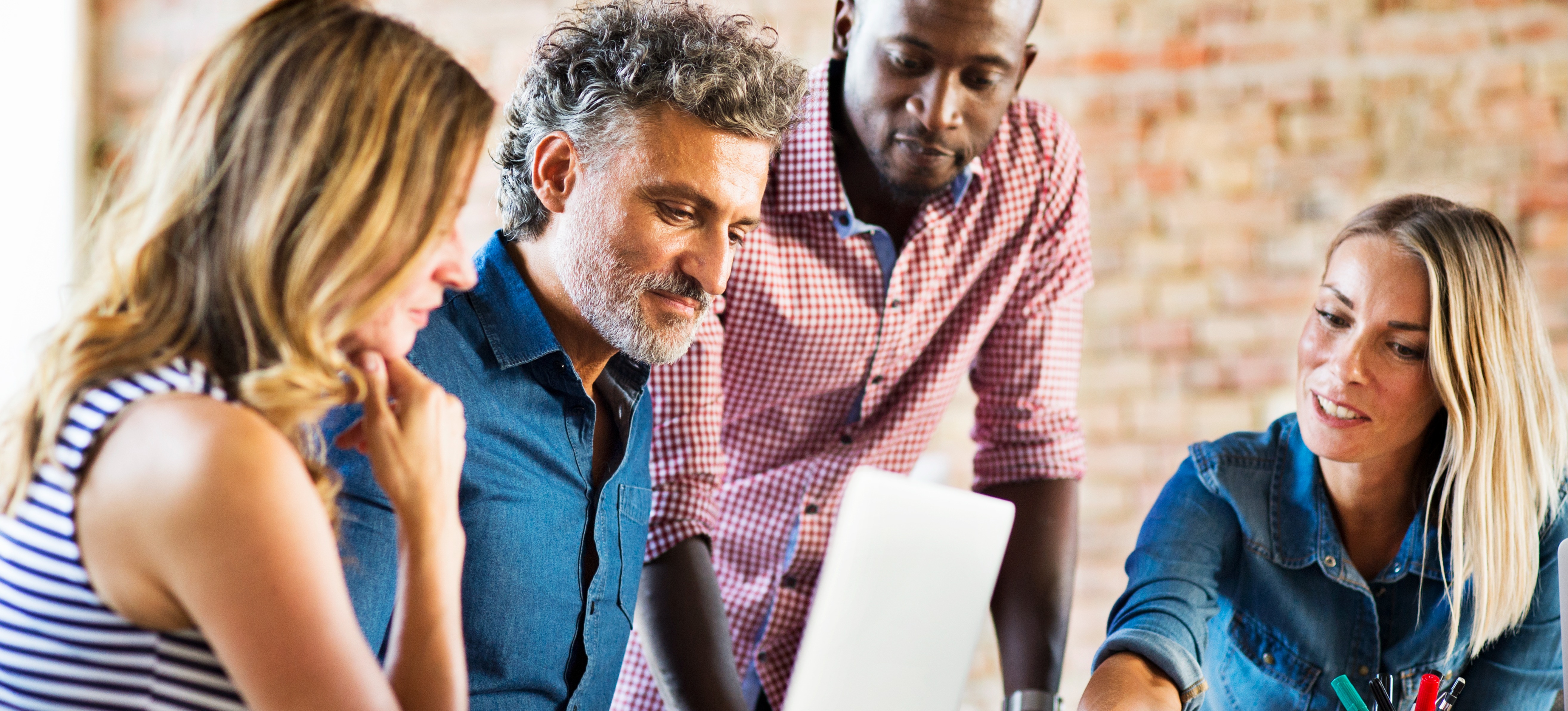 [Featured Image] A group of finance employees sit around a laptop and discuss using predictive analytics for forecasting cash flow.