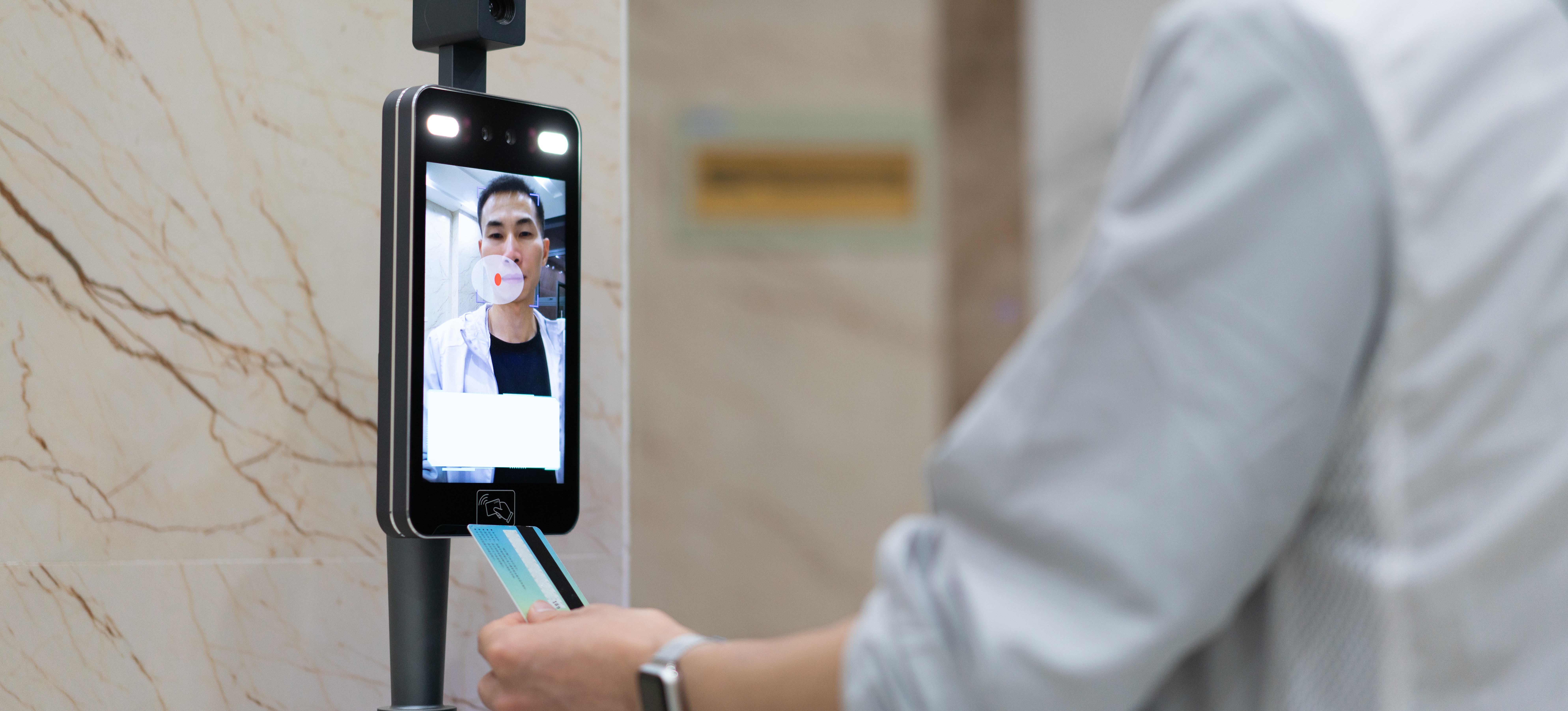 [Featured Image] A person uses facial recognition to get into their office.