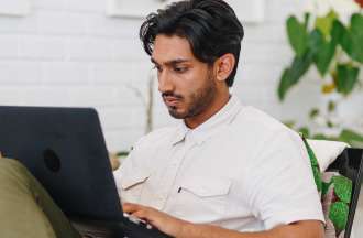Featured image: A man wearing a white shirt looking at a laptop screen and typing.