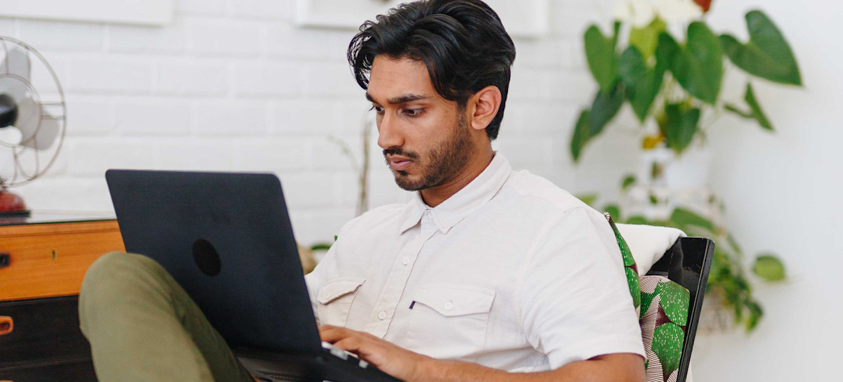 Featured image: A person wearing a white shirt looking at a laptop screen and typing.