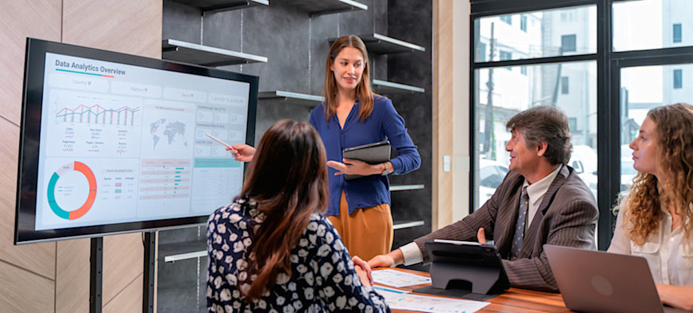 [Featured Image] A group of business intelligence analysts discuss data visualizations on a BI dashboard.
