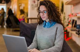 [Featured Image] A DevOps engineer works on their resume in a coffee shop while looking at their laptop.